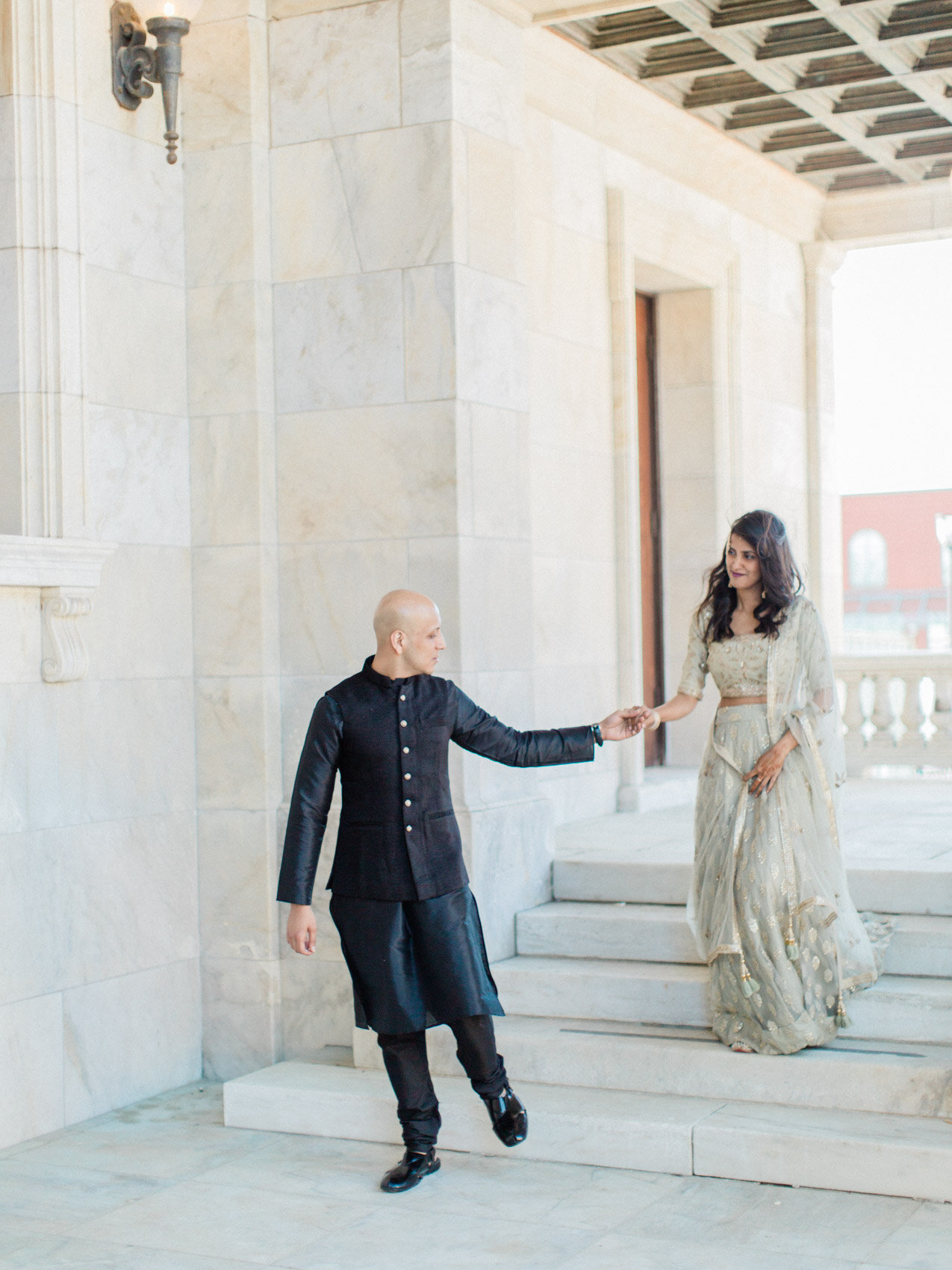 A chic indian couple posing naturally on the court house steps for their engagement photographs