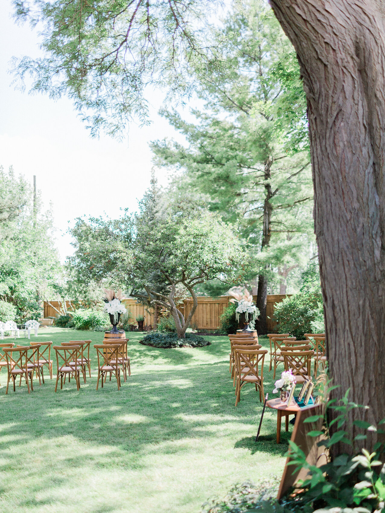 a backyard wedding set up with harvest chairs and an apple tree