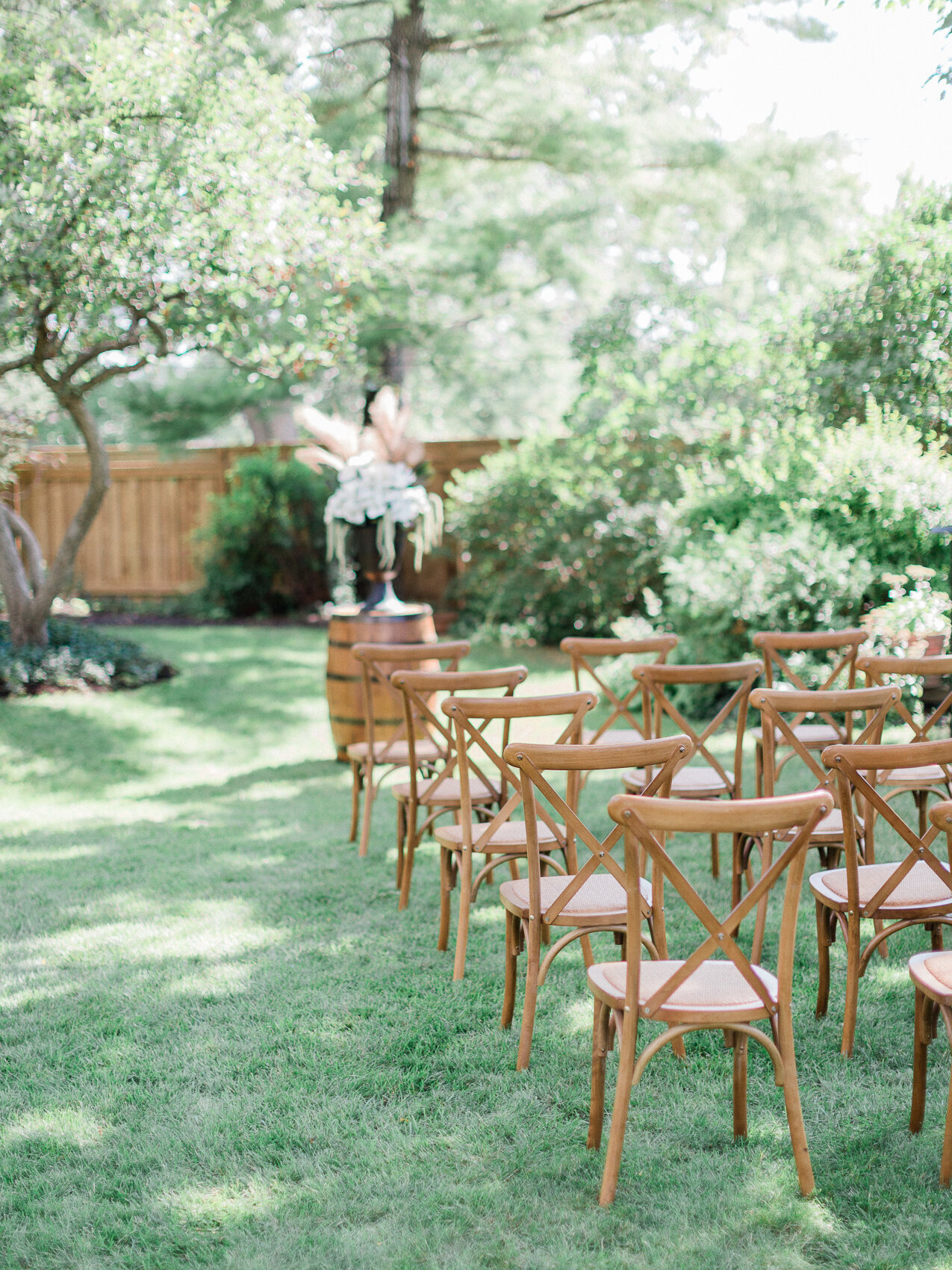 a backyard wedding set up with harvest chairs and an apple tree