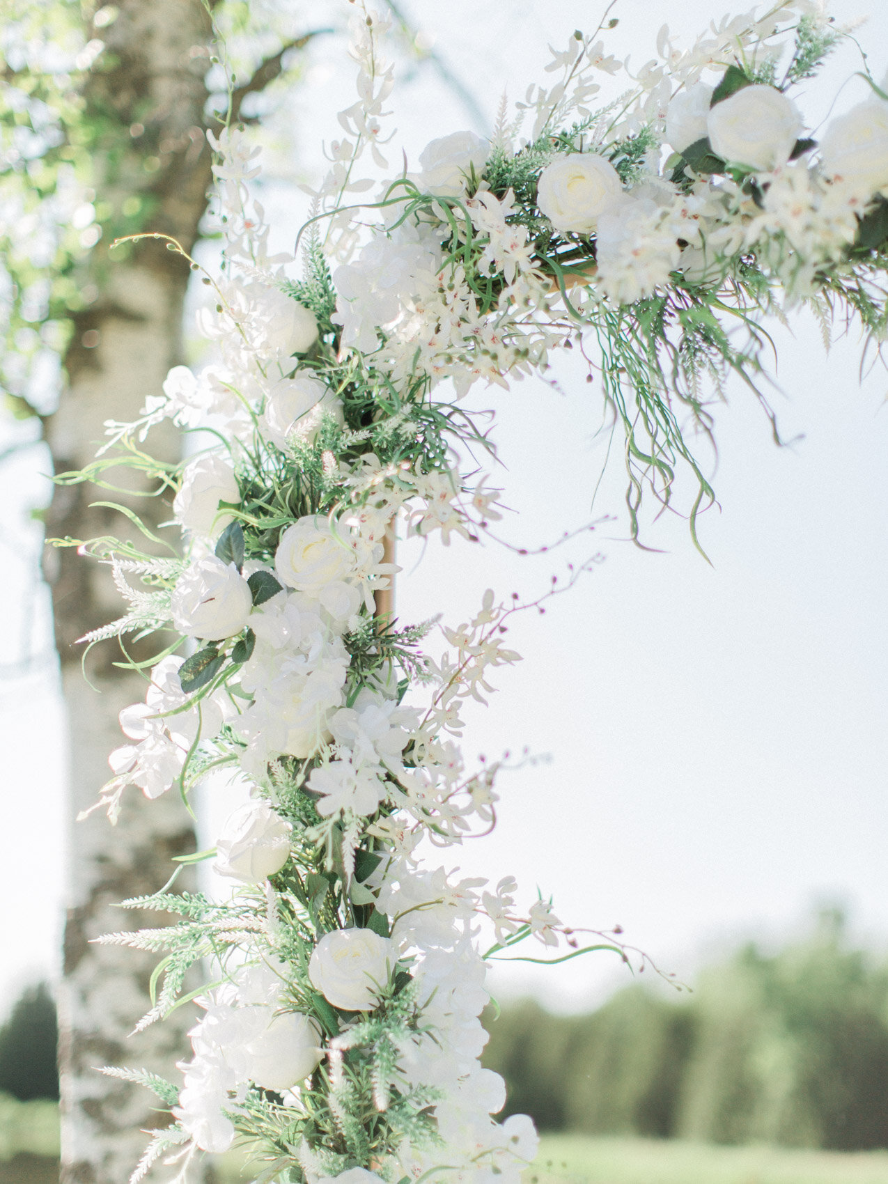 a white and green minimal floral wedding arch