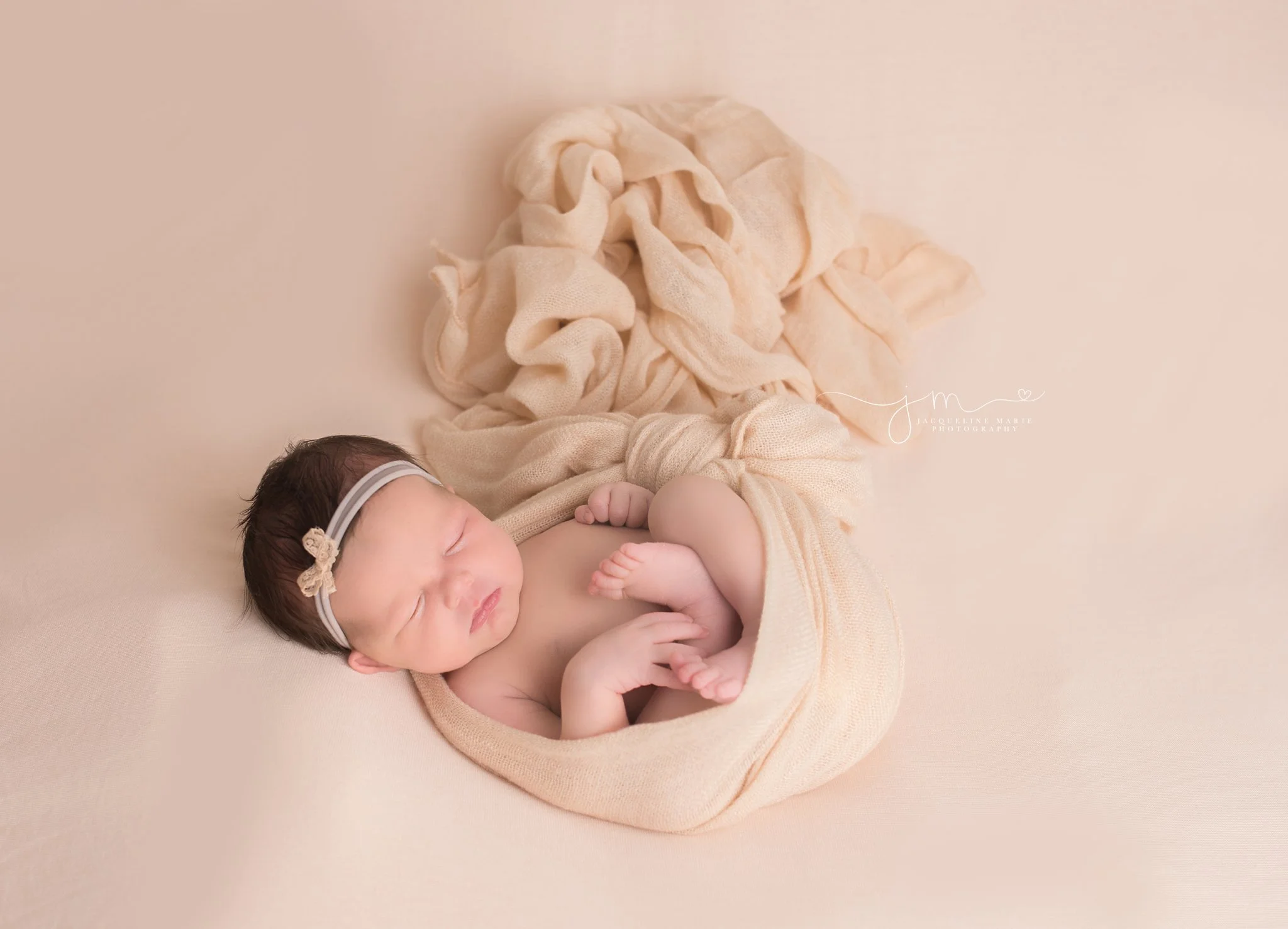 newborn photography by jacqueline marie photography features baby girl wrapped in blush pink layer