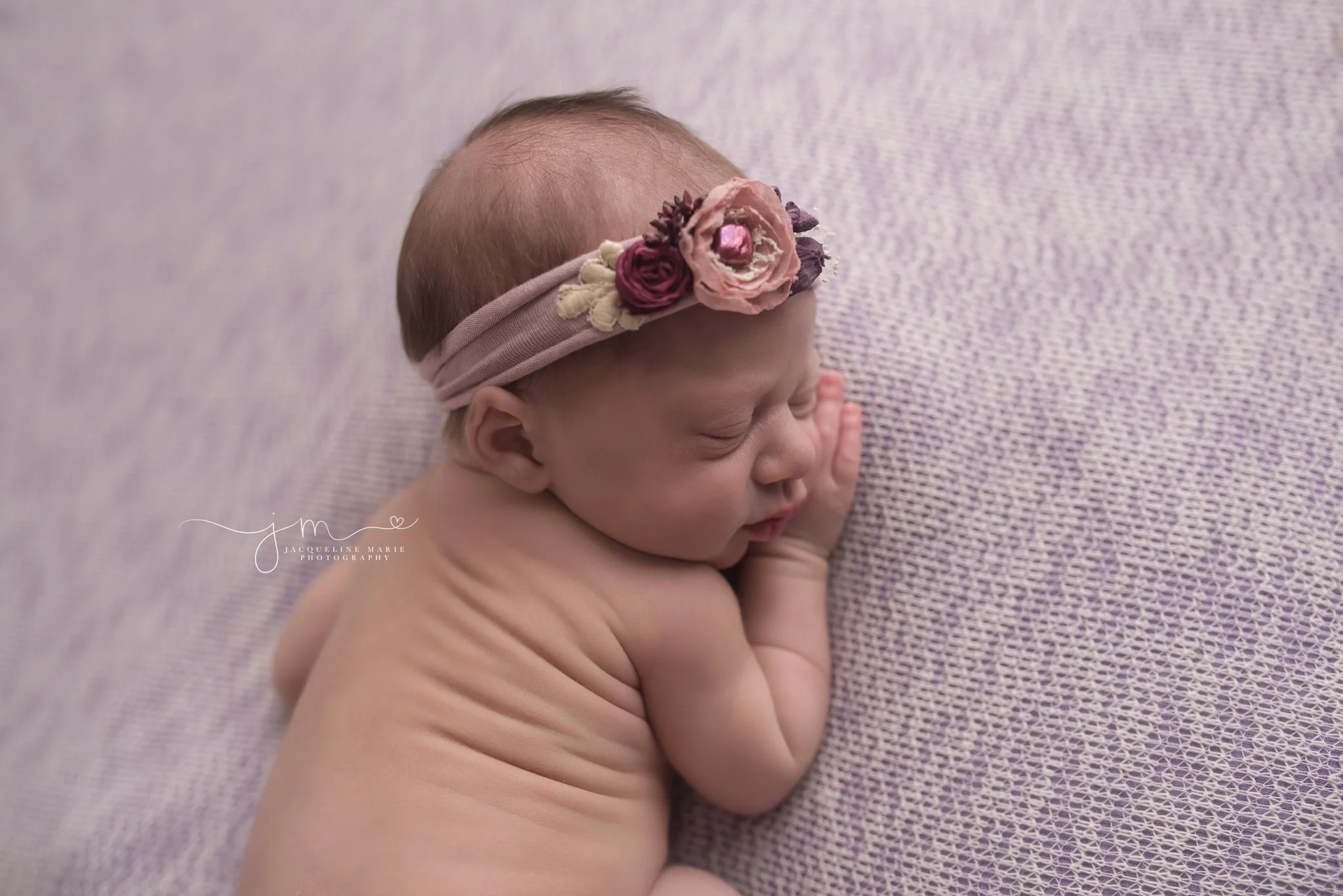 Newborn photography portrait features 9 day old baby girl wearing pink and purple headband with focus on facial features in Columbus Ohio