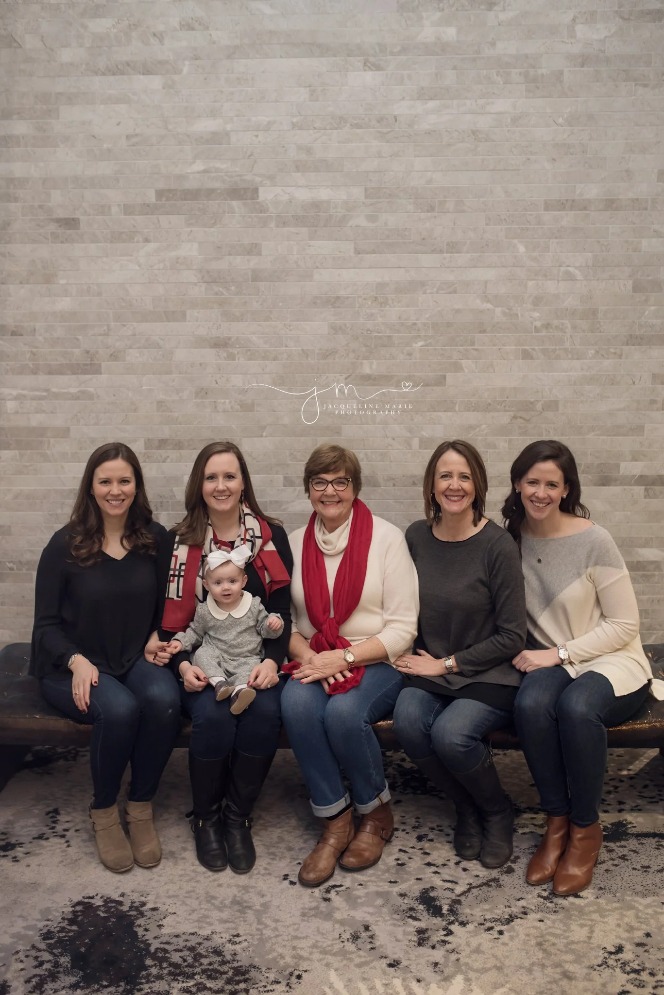 Granddaughters sit with great grandmother wearing jeans and sweaters inside Hilton Hotel in Columbus Ohio for family portraits