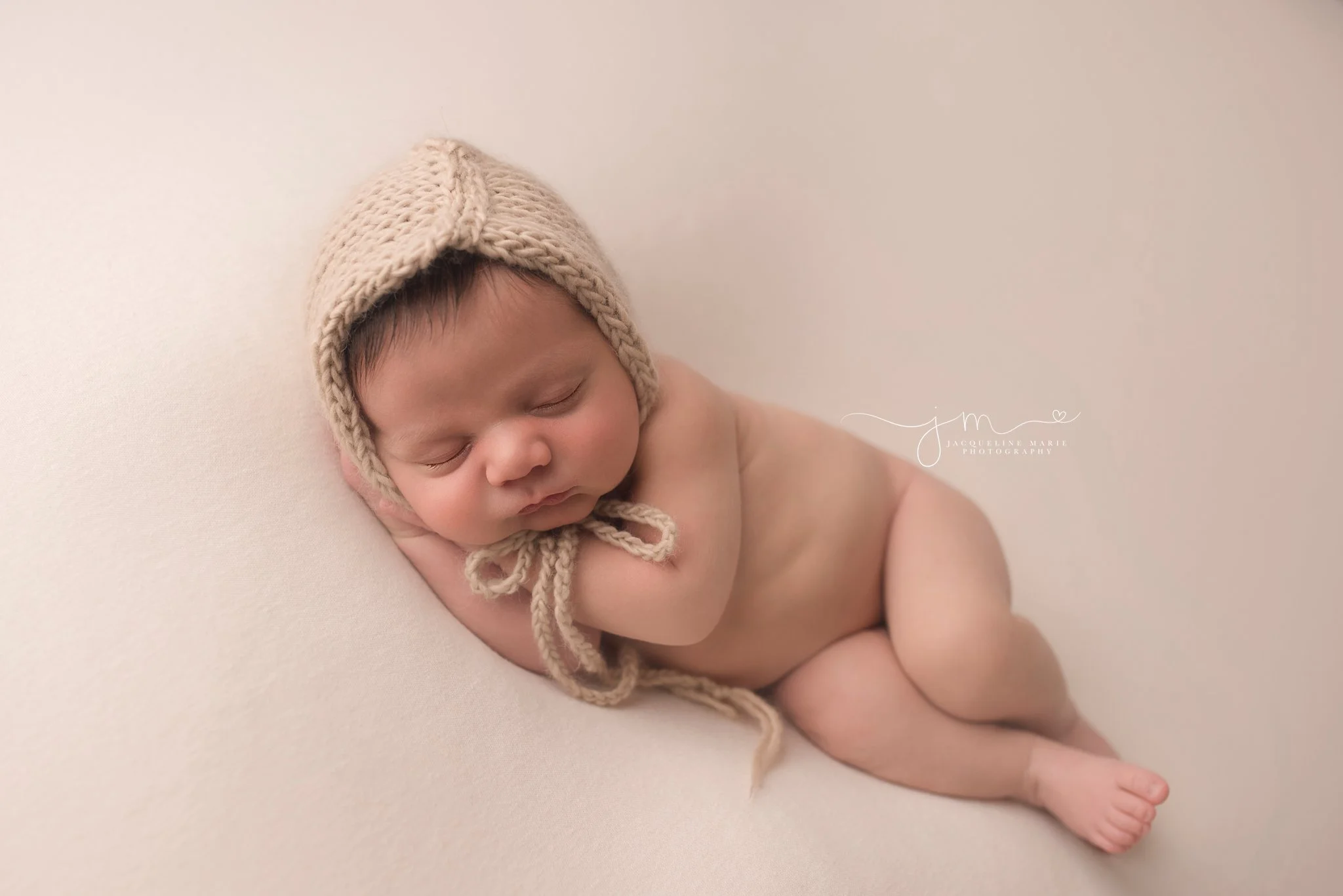 newborn portrait features baby sleeping wearing tan bonnet by newborn photographer in columbus ohio