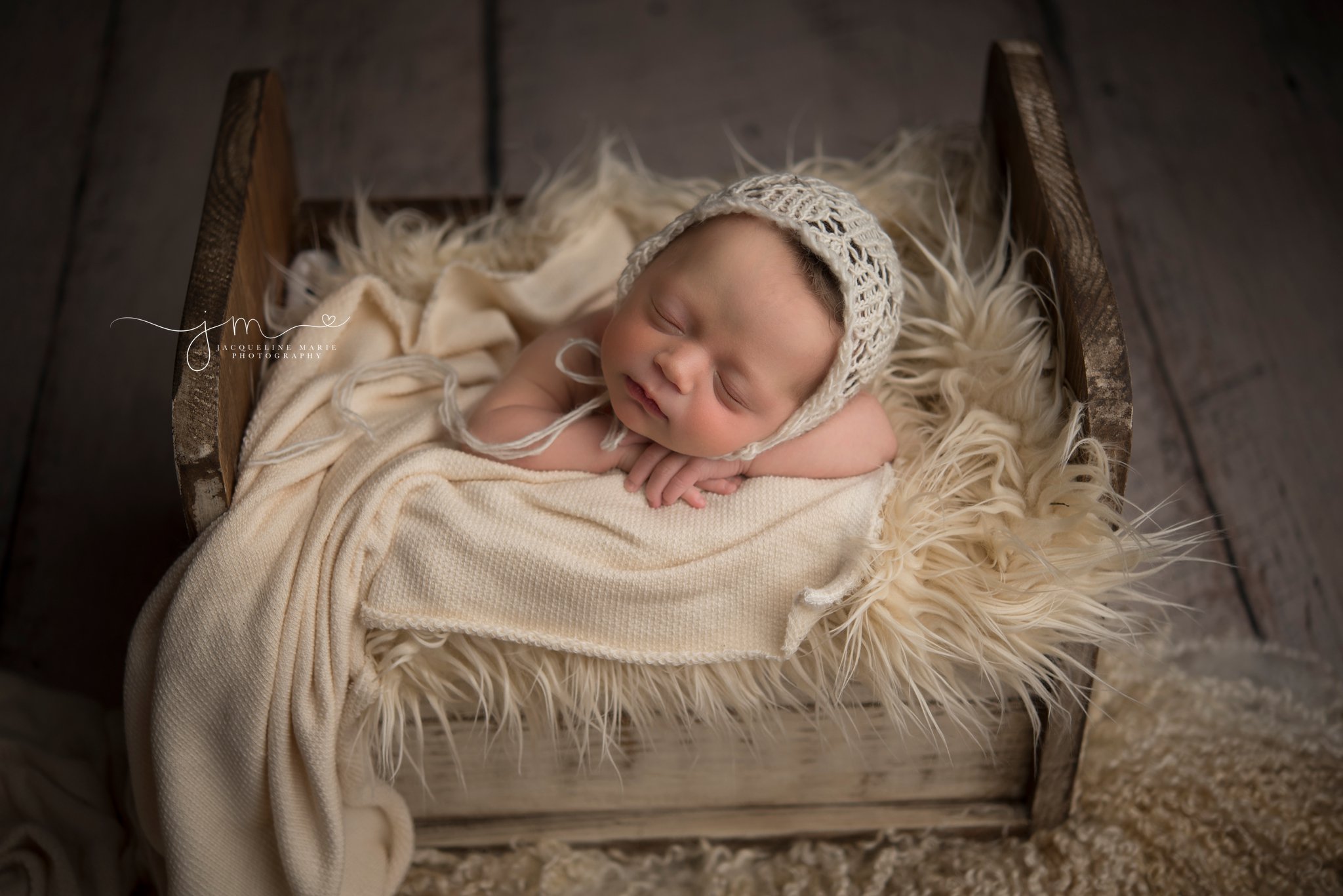 columbus ohio newborn photographer poses newborn baby in wood bed for newborn mentoring session with Photograpy by axis design in toccoa georgia