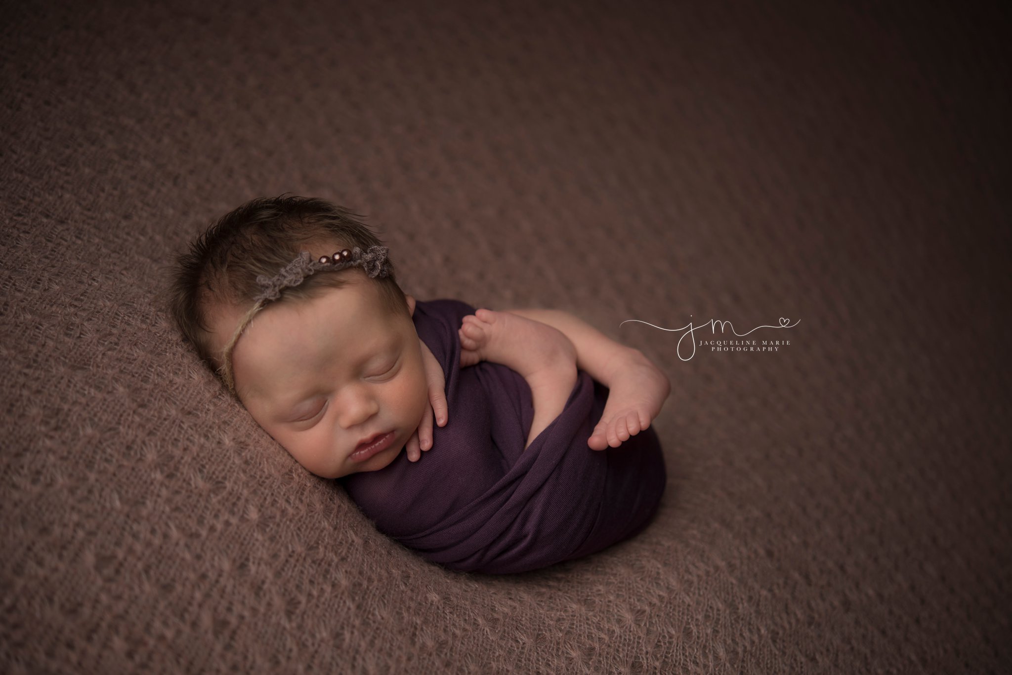 5 day old newborn baby girl is swaddled in purple wrap for newborn photography portraits by columbus ohio newborn photographer jacqueline marie photography
