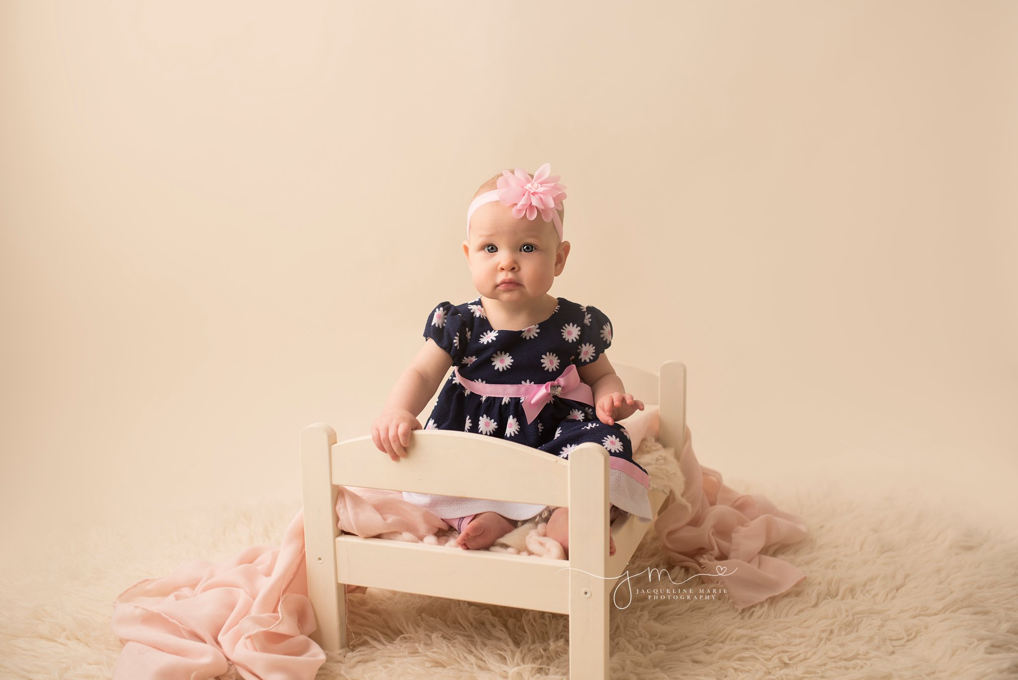 9 month old bay girl sits on cream bed for baby milestone pictures in columbus ohio