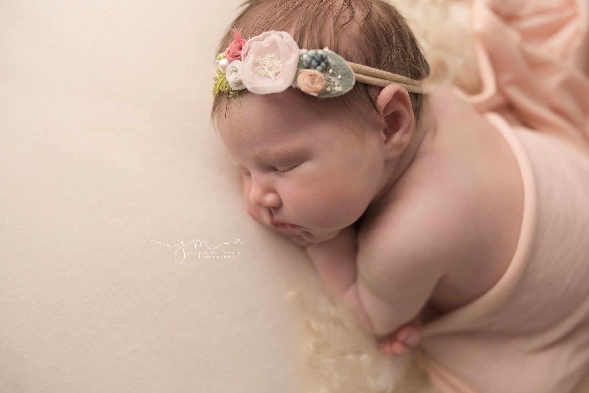 newborn photography portrait features baby girl wearing pastel headband and pink wrap in columbus ohio
