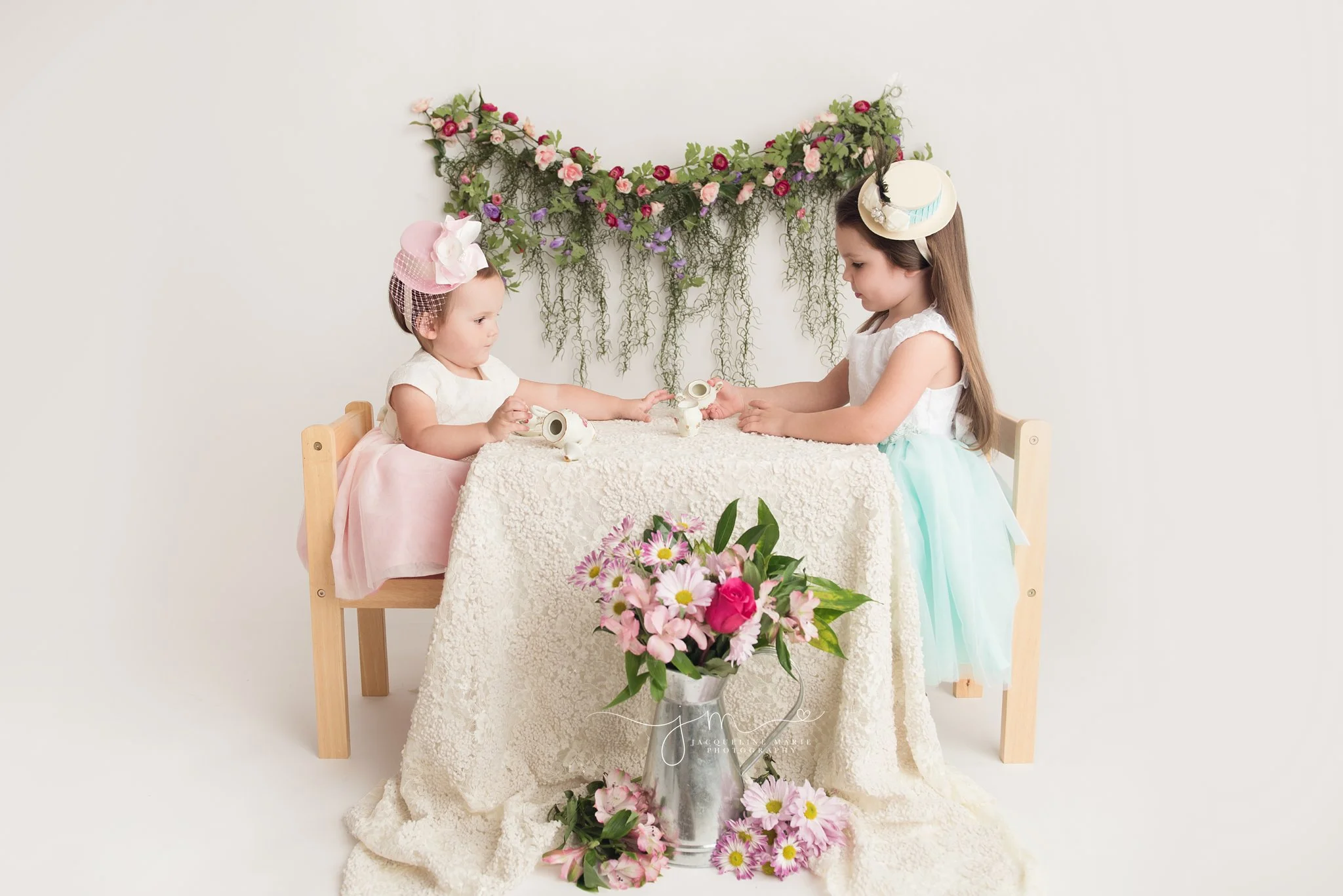 columbus ohio children photographer features sisters having a vintage tea party wearing dresses and hats at jacqueline marie photography studio
