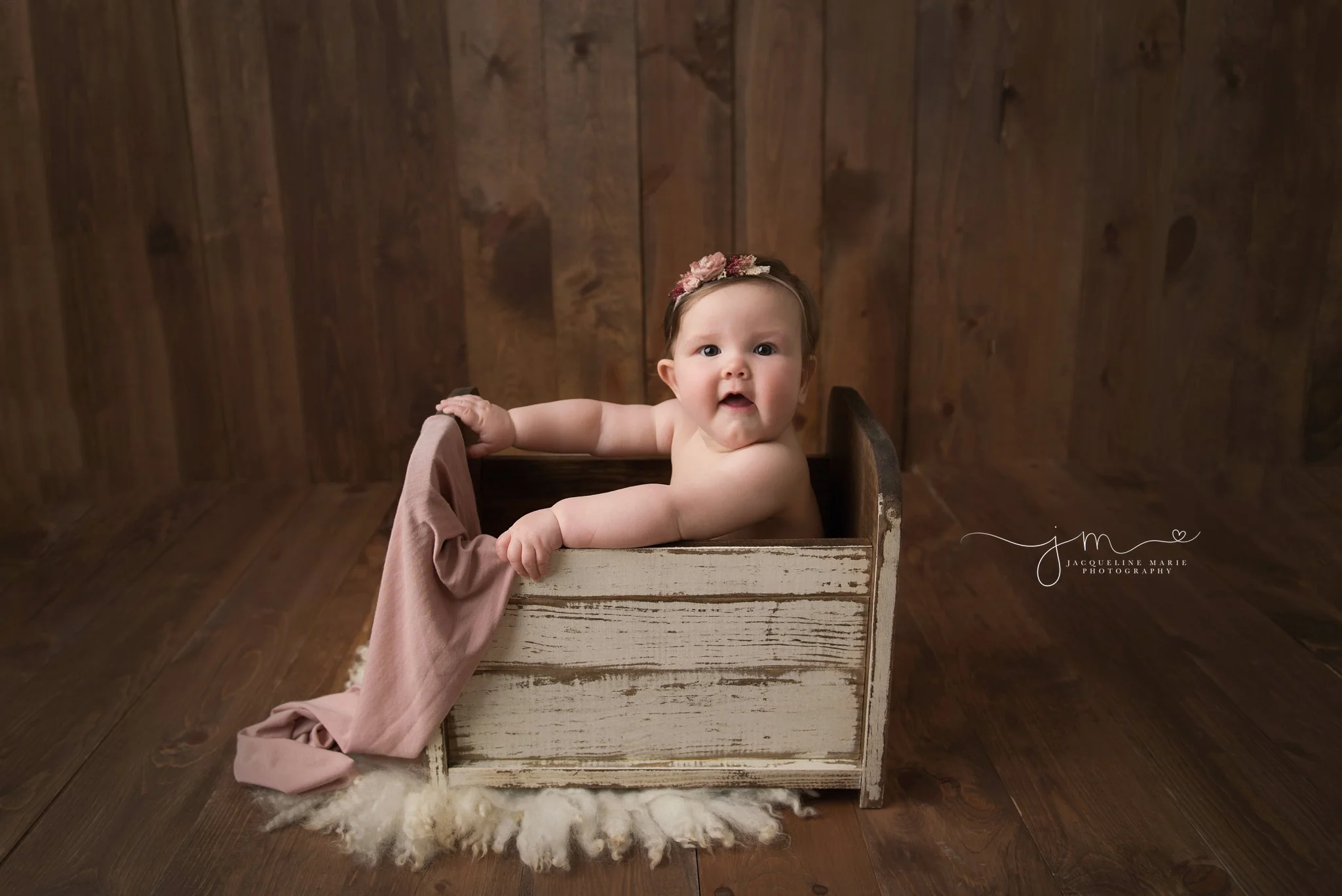 6 month old baby girl wears pink floral headband and sits in white wooden bed for milestone baby pictures in columbus ohio