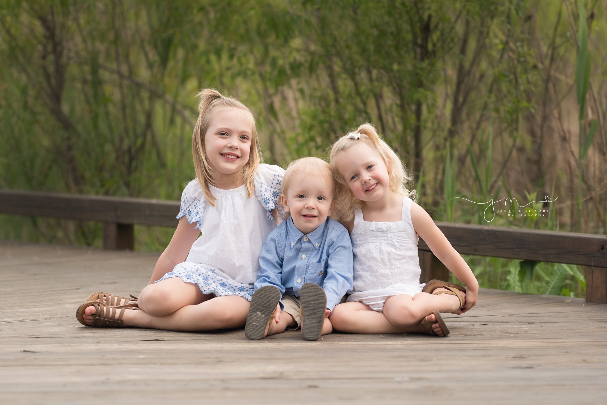 columbus ohio family and children photographer features image of brother and older sisters sitting on wood bridge at a park