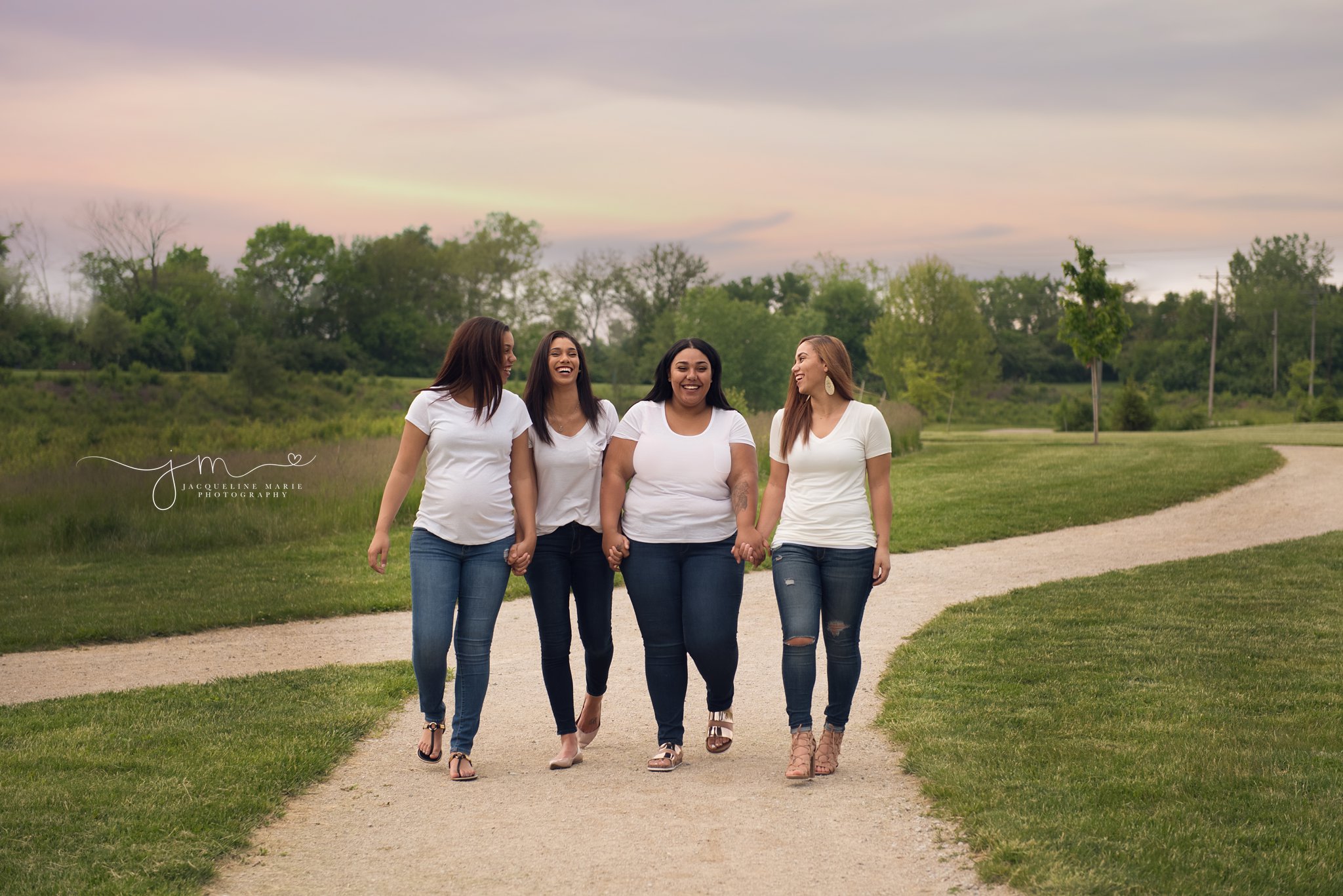 four sisters walk together laughing and holding hands in columbus ohio for family photography pictures