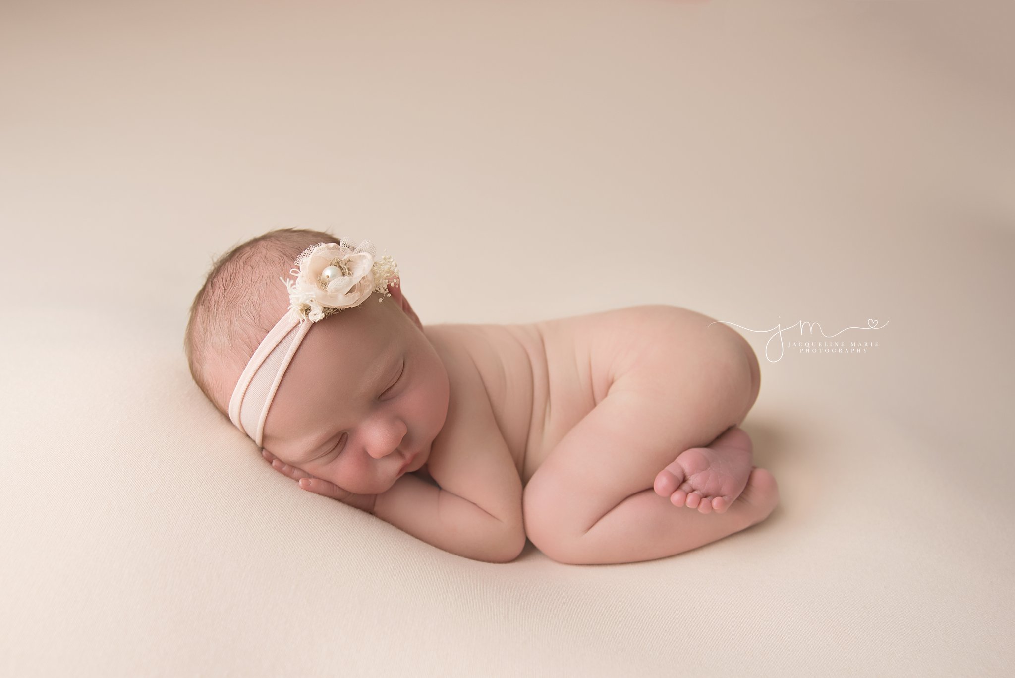 newborn baby girl wears blush pink headband while sleeping for newborn photography pictures in columbus ohio