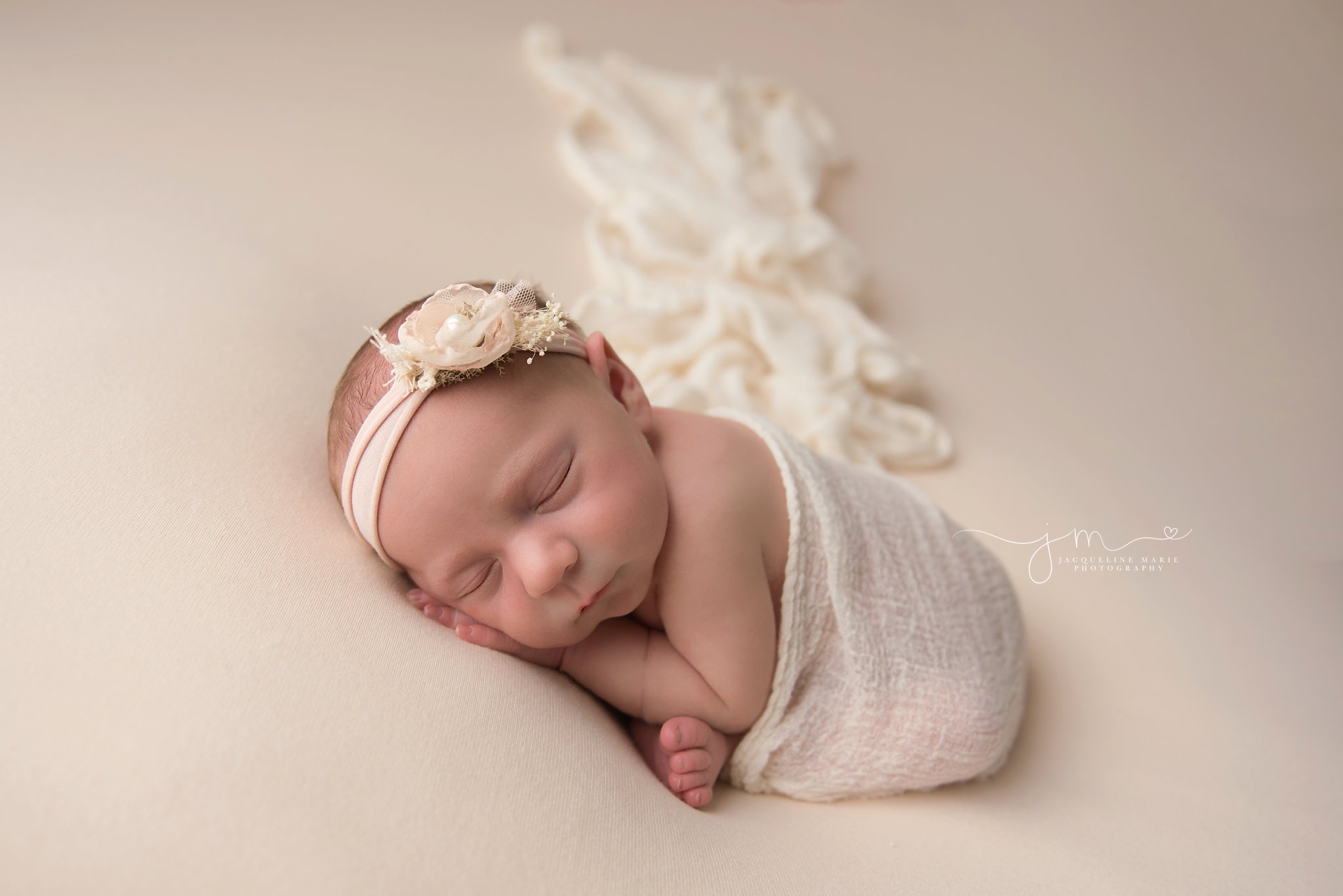 1 week old newborn baby girl is wrapped in cream wrap and matching headband for newborn portraits in columbus ohio