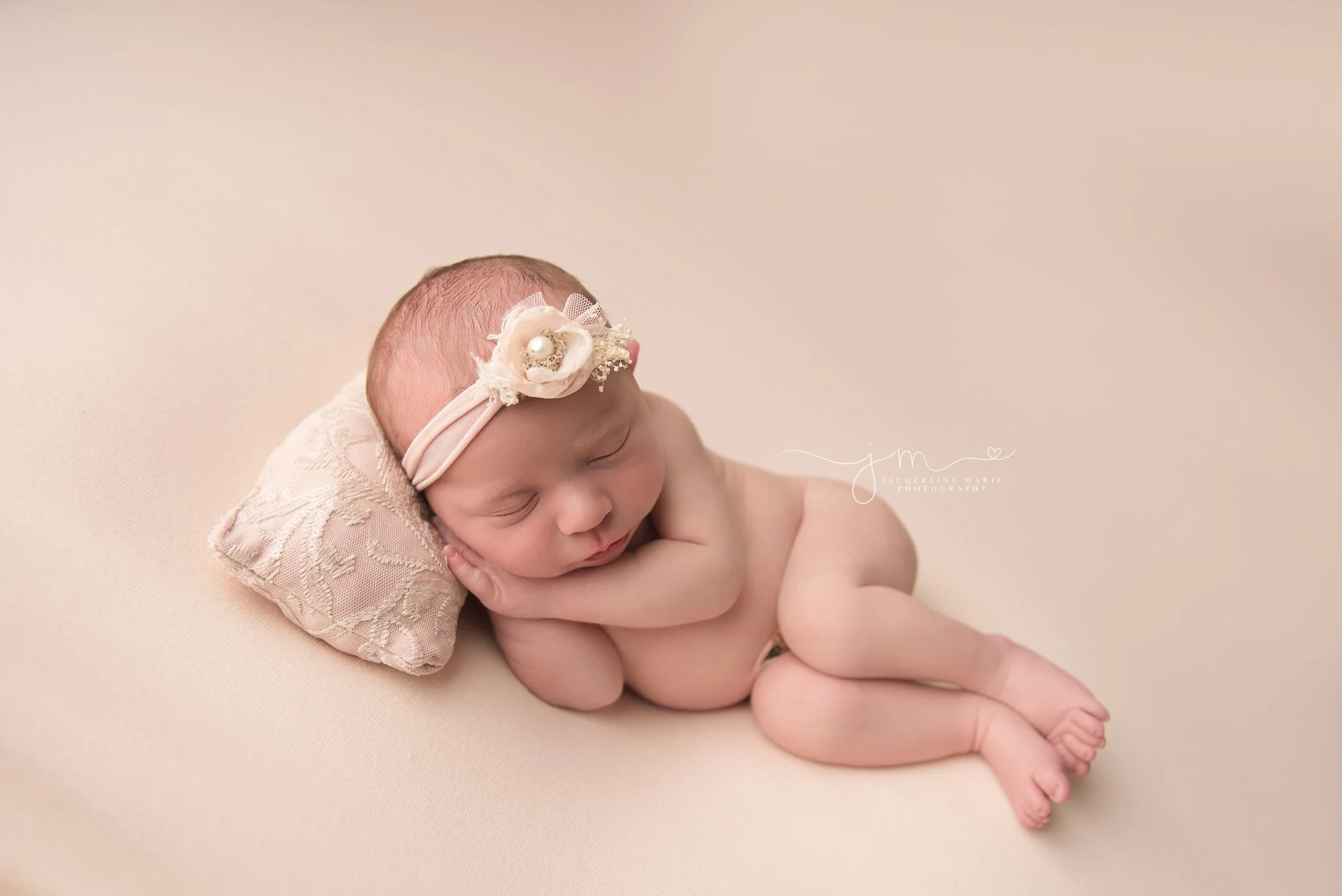 columbus ohio newborn photographer features baby girl sleeping on beaded pillow and wearing pink headband with a pearl
