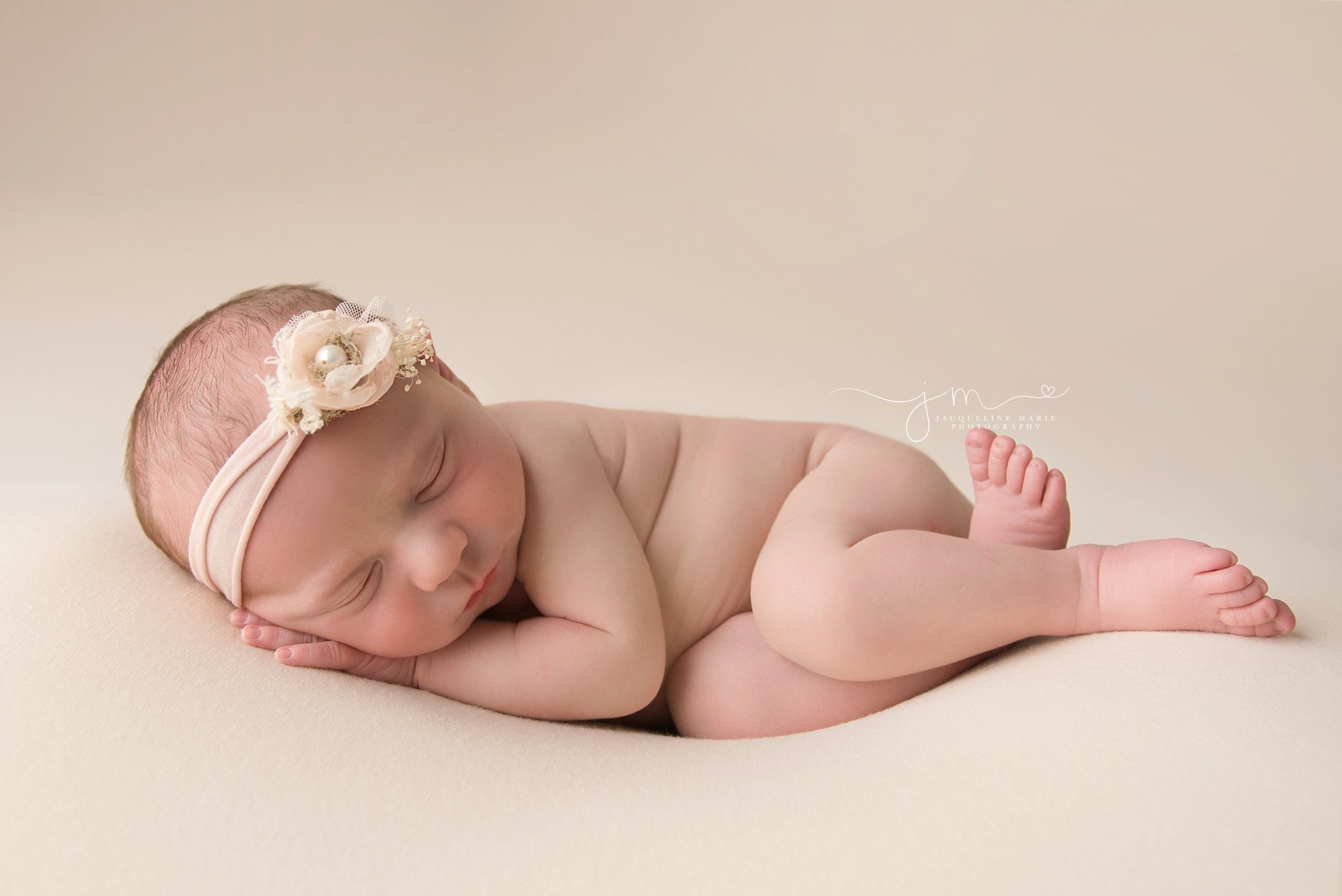 one week old baby girl Lyla sleeps with her hand on her cheek at newborn photography studio in columbus ohio