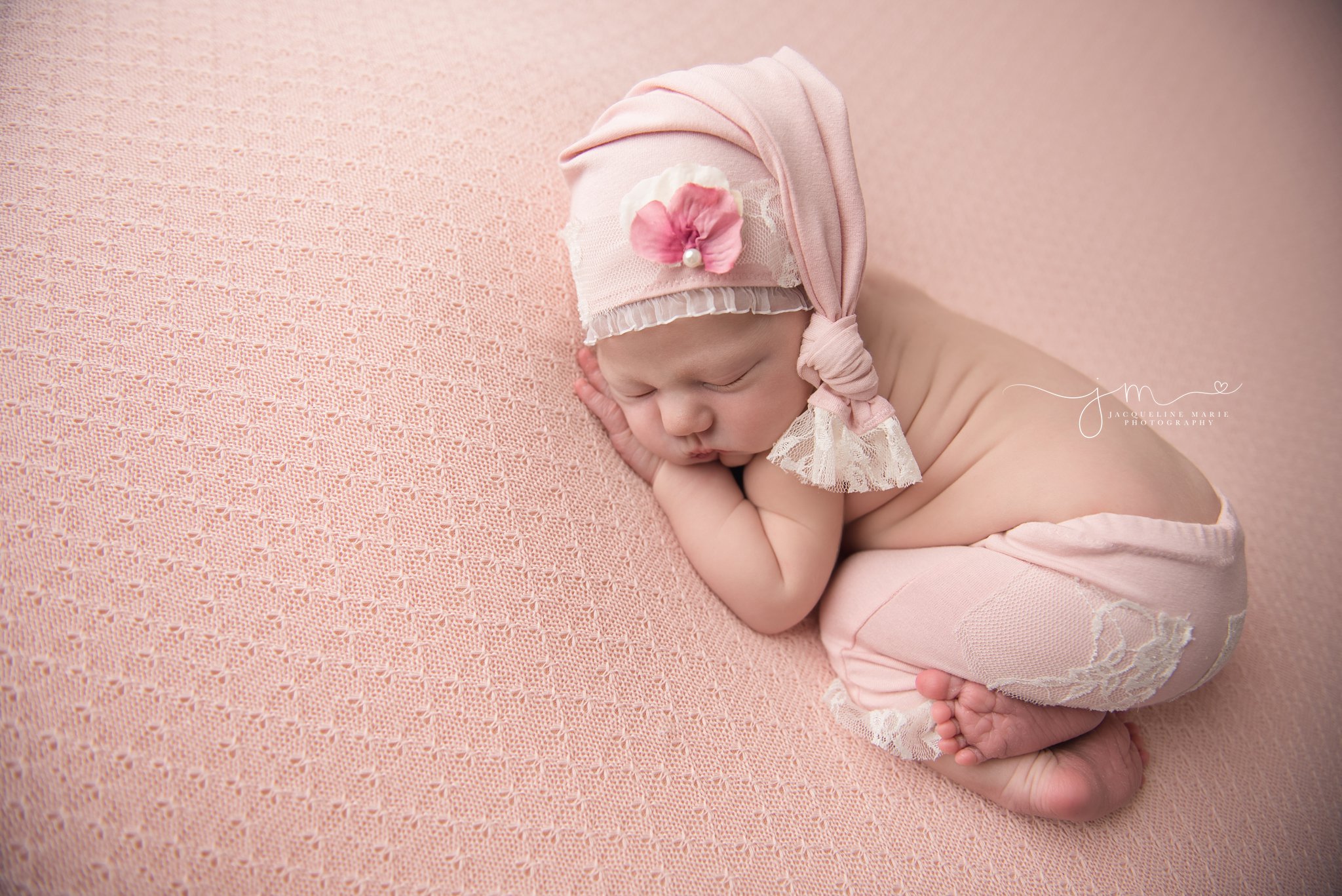 1 week old newborn baby girl wears matching pants and pink hat for newborn photography pictures in columbus ohio