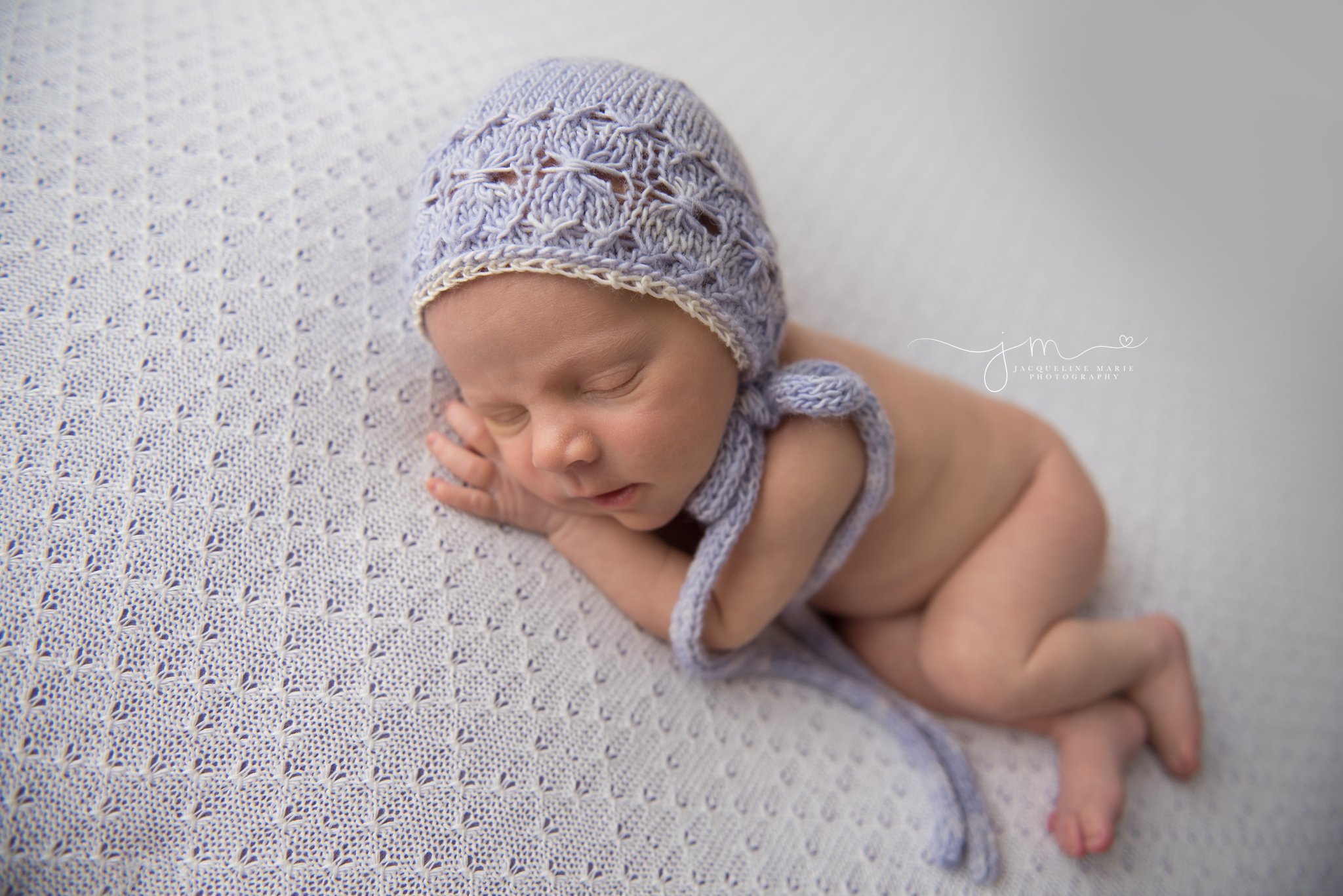 newborn baby girl wears purple knit bonnet while sleeping for newborn photography pictures in columbus ohio