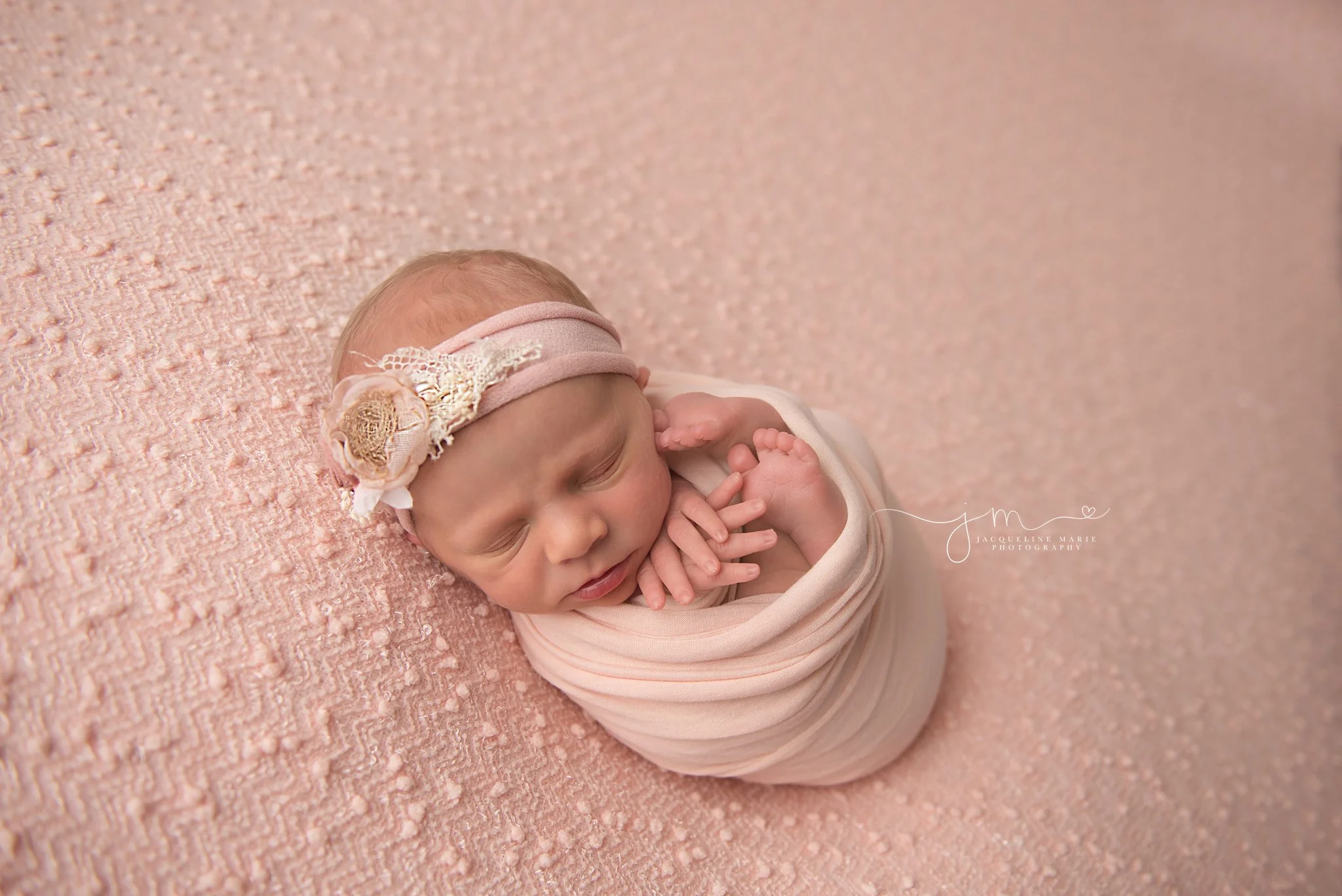 columbus ohio newborn photographer features image of newborn baby girl swaddled in pink wrap and matching headband 