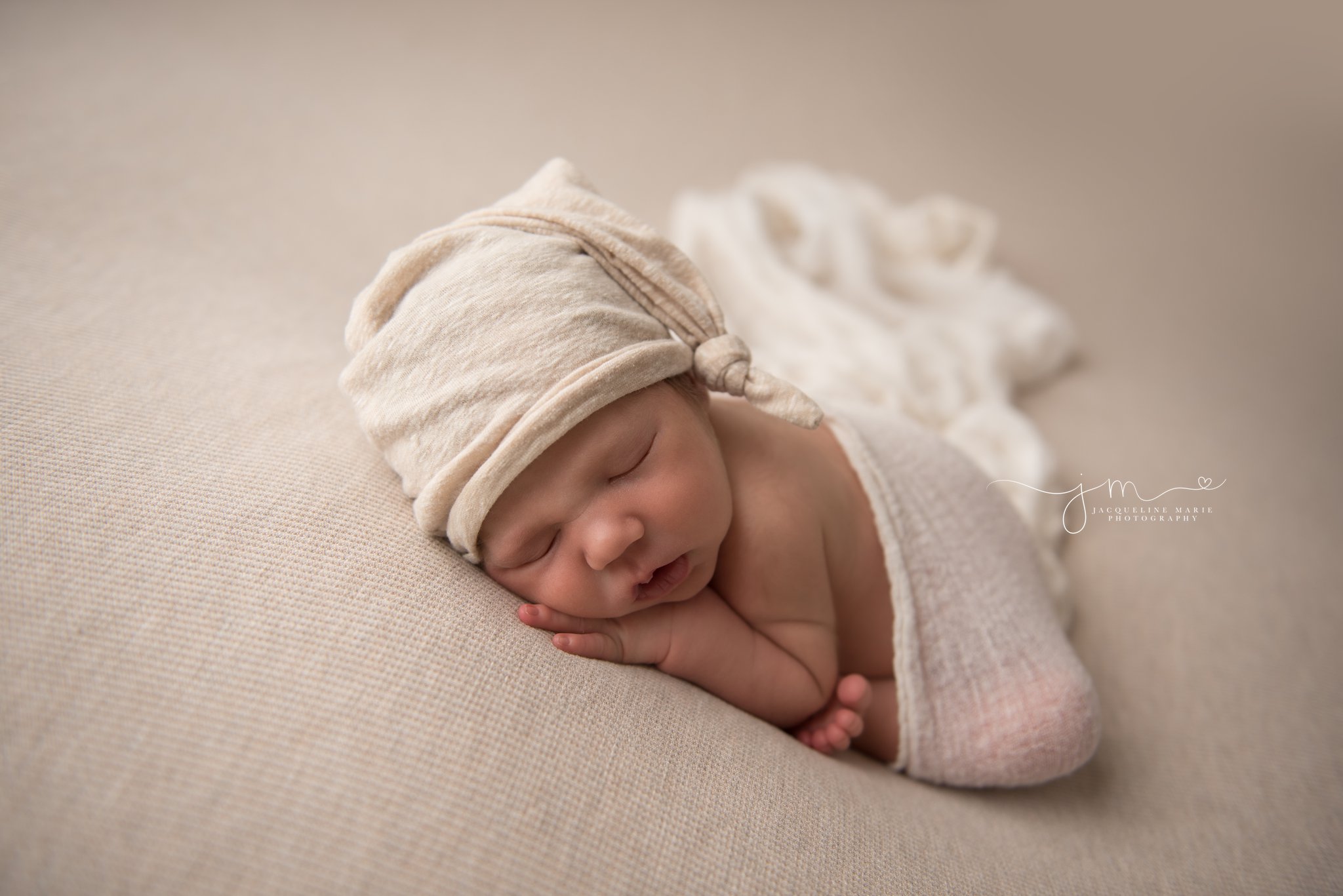 columbus ohio newborn baby boy wears cream hat and is swaddled in cream wrap at jacqueline marie photography studio
