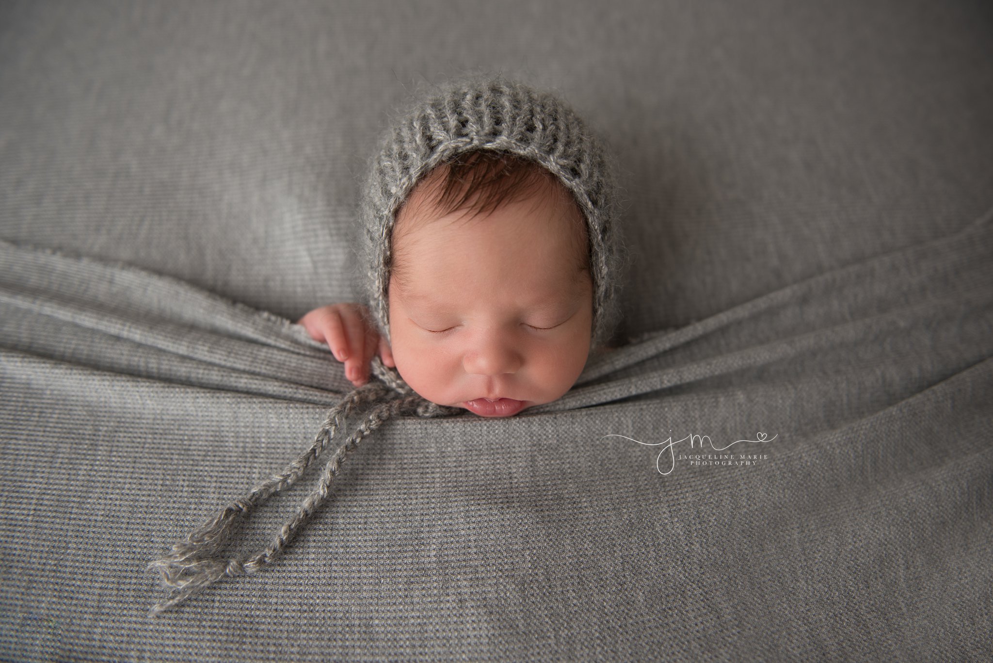 columbus ohio newborn baby boy wears gray bonnet with hands peeking out of gray blanket at jacqueline marie photography studio