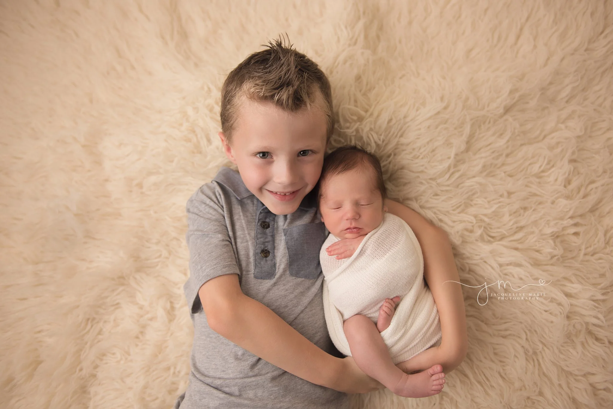 big brother holds newborn baby brother and smiles in columbus ohio for newborn photography pictures