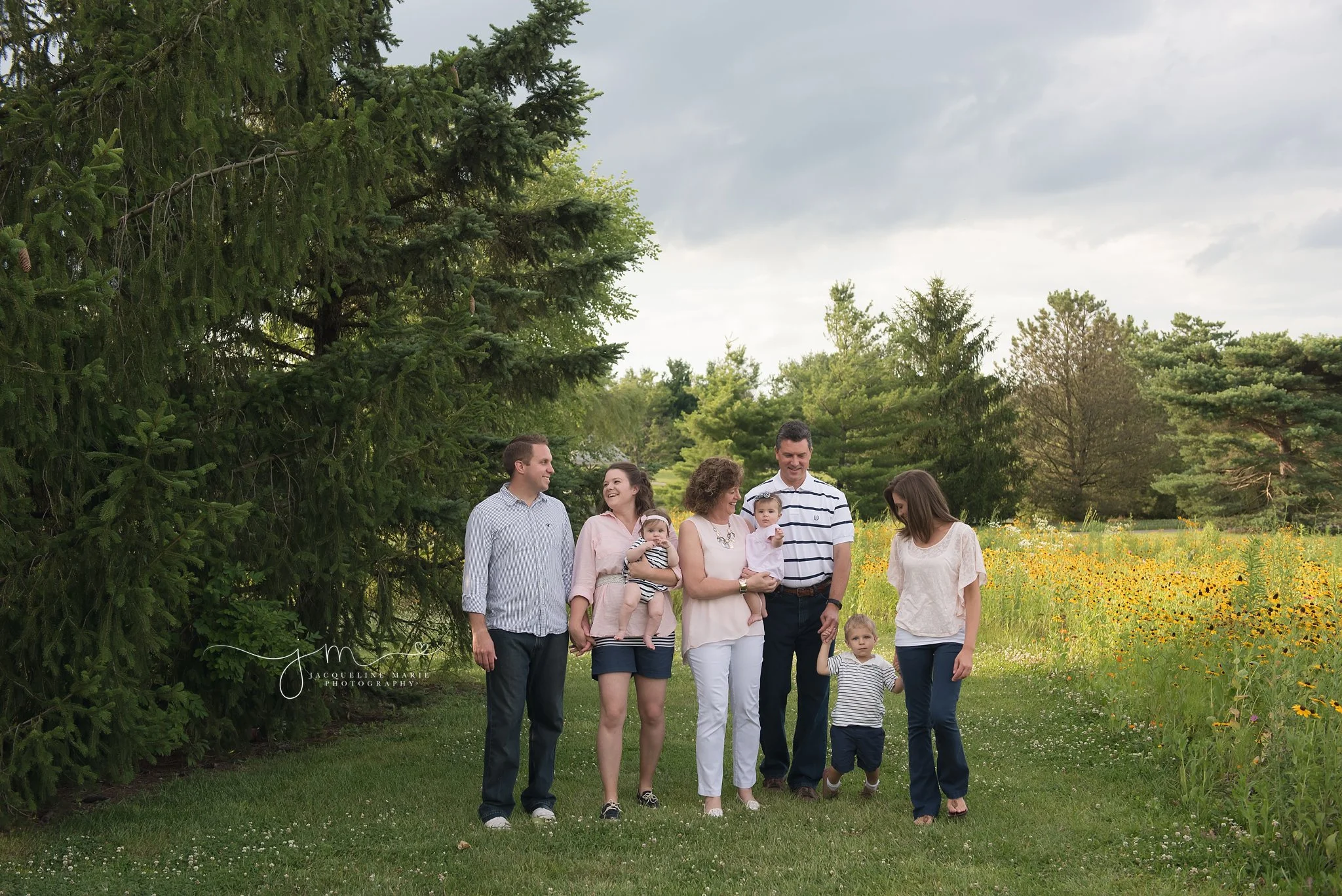 columbus ohio family photographer features family walking and holding hands while smiling in a field of flowers