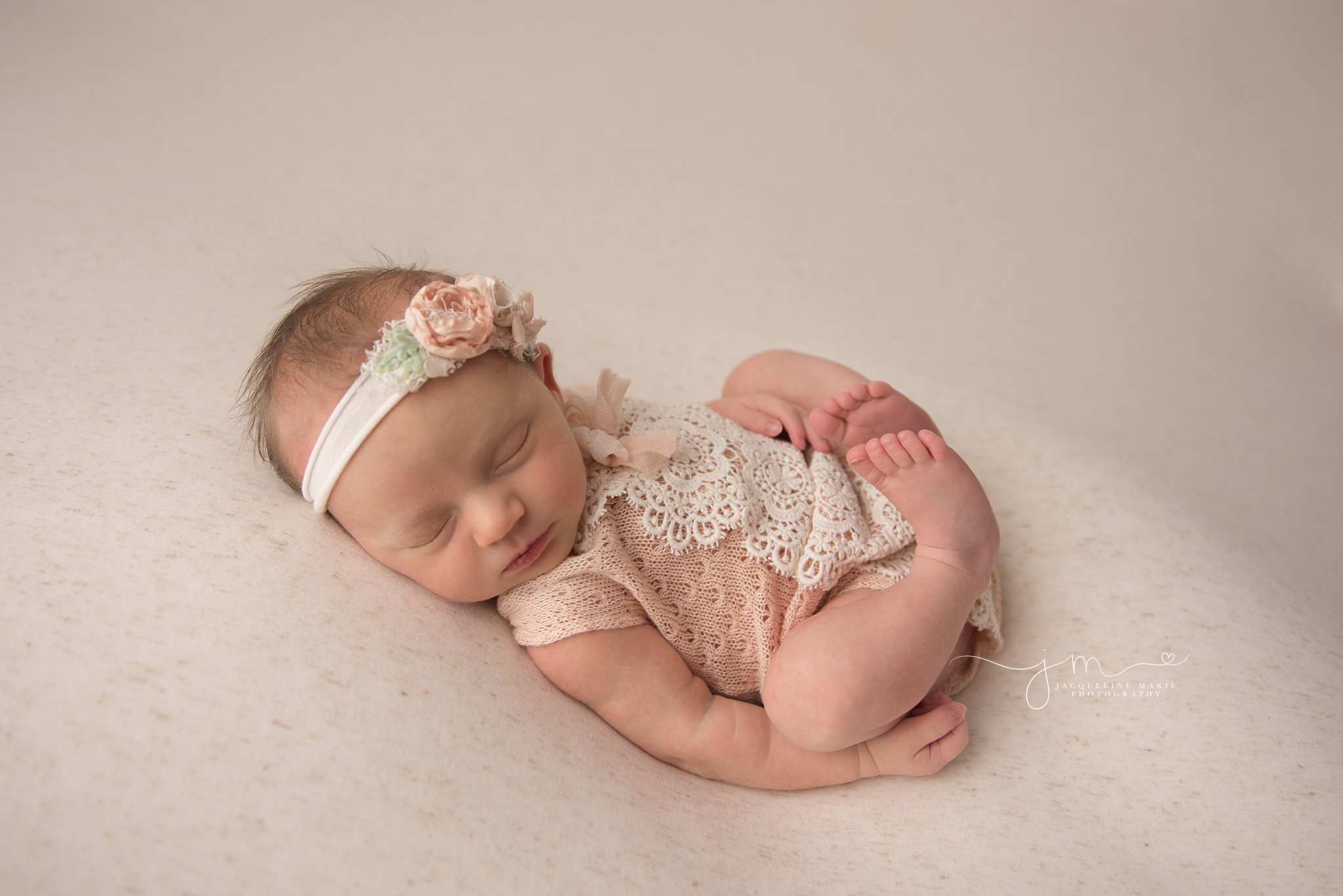 columbus ohio newborn photographer poses baby girl in peach and cream lace romper while sleeping 