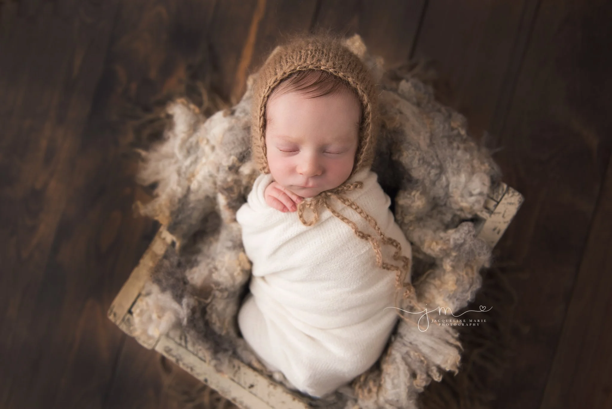 columbus ohio newborn baby boy is swaddled in cream wrap and tan bonnet for newborn pictures at jacqueline marie photography studio
