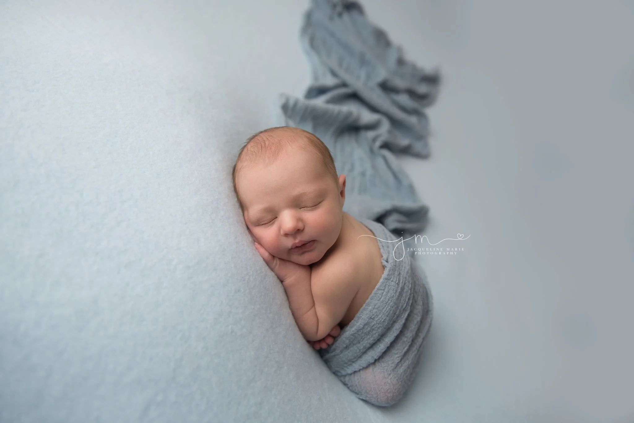 newborn baby boy is wrapped in blue blanket while sleeping for newborn photography portraits in columbus ohio