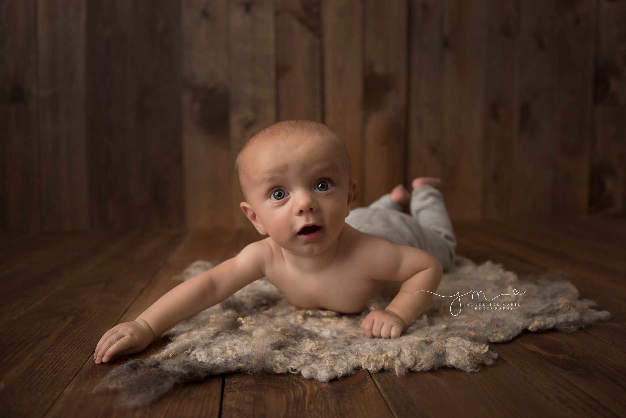 6 month old baby boy wears gray pants while on his belly at baby portrait studio in columbus ohio