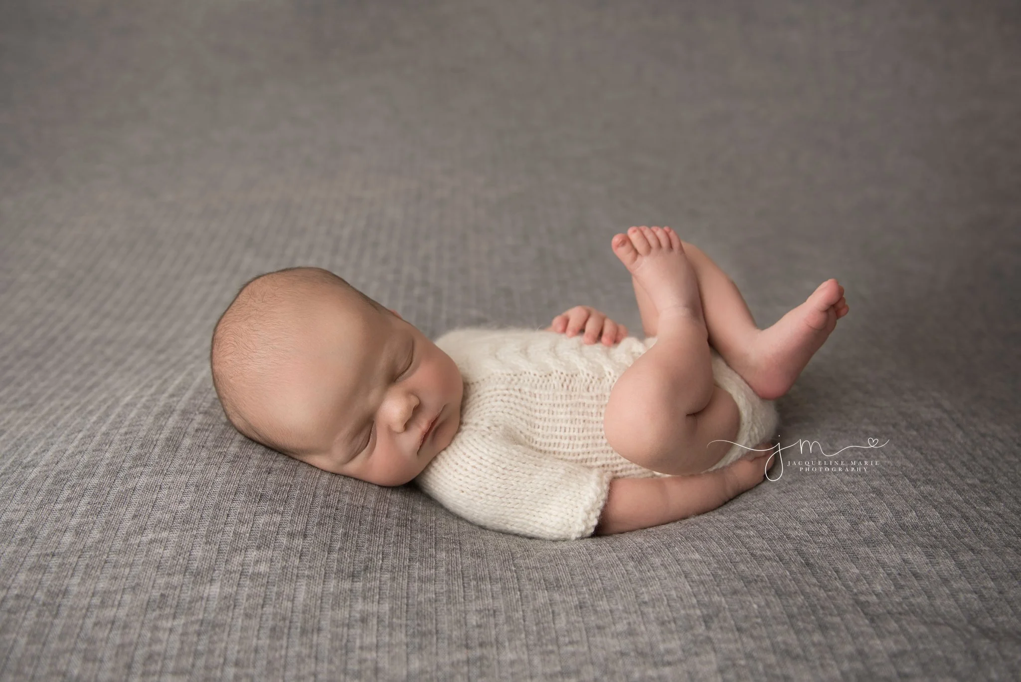 columbus ohio newborn wears cream sweater romper for newborn photography session 