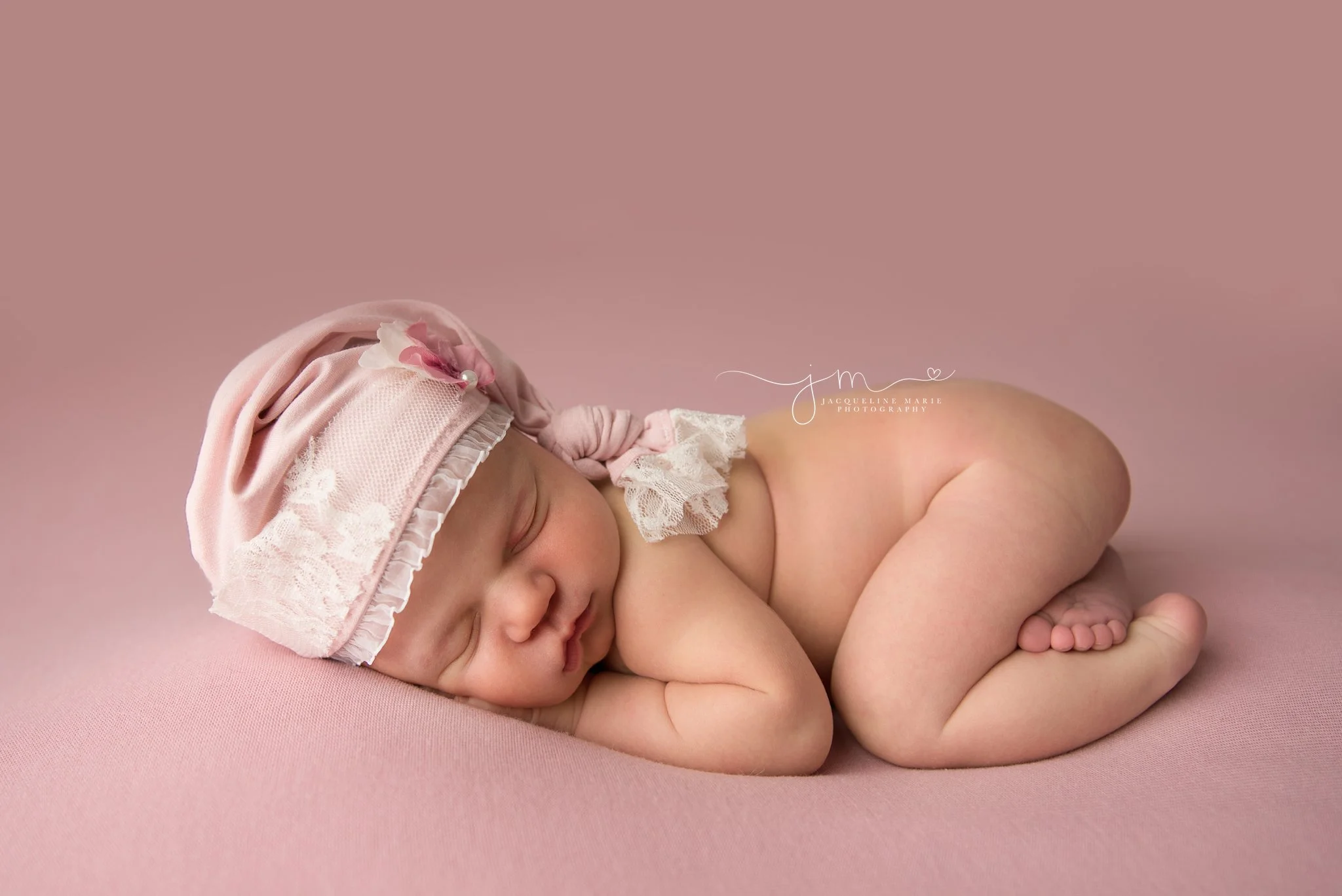 1 week old newborn baby girl wears pink and white lace sleepy hat in columbus ohio for newborn photography session