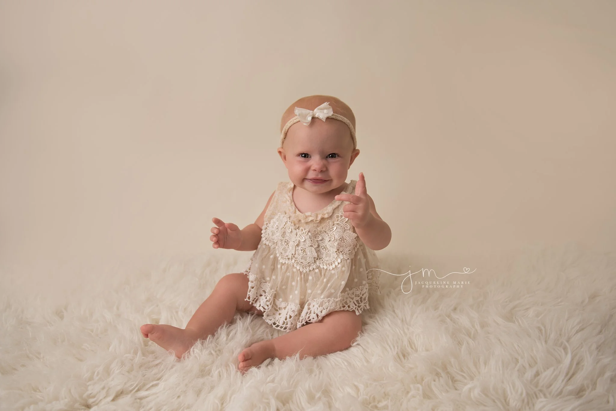 1 year old baby girl smiles on cream rug for first birthday photo session in columbus ohio