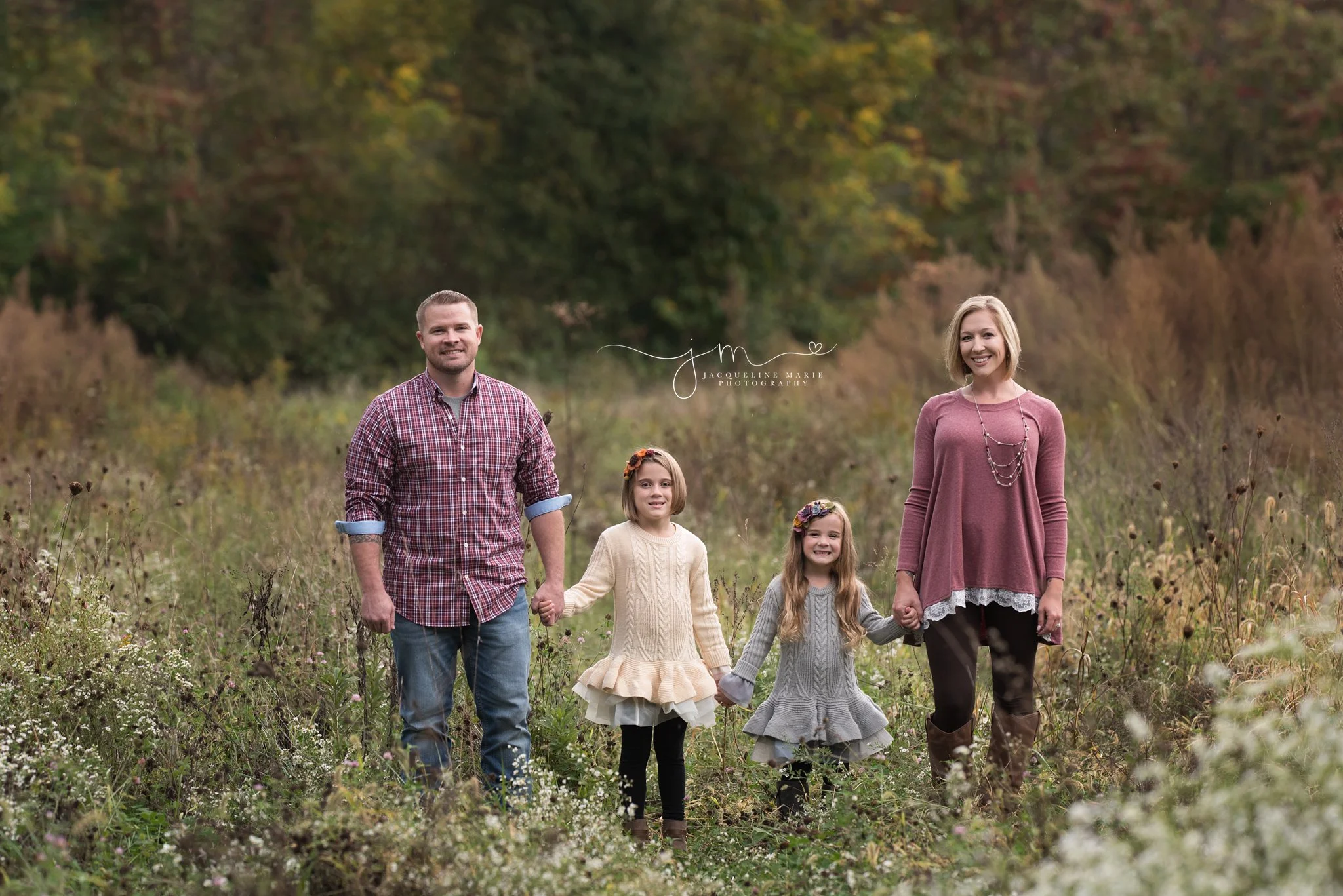 family of four from pickerington ohio holds hands and smiles in a field during their fall family photography session 