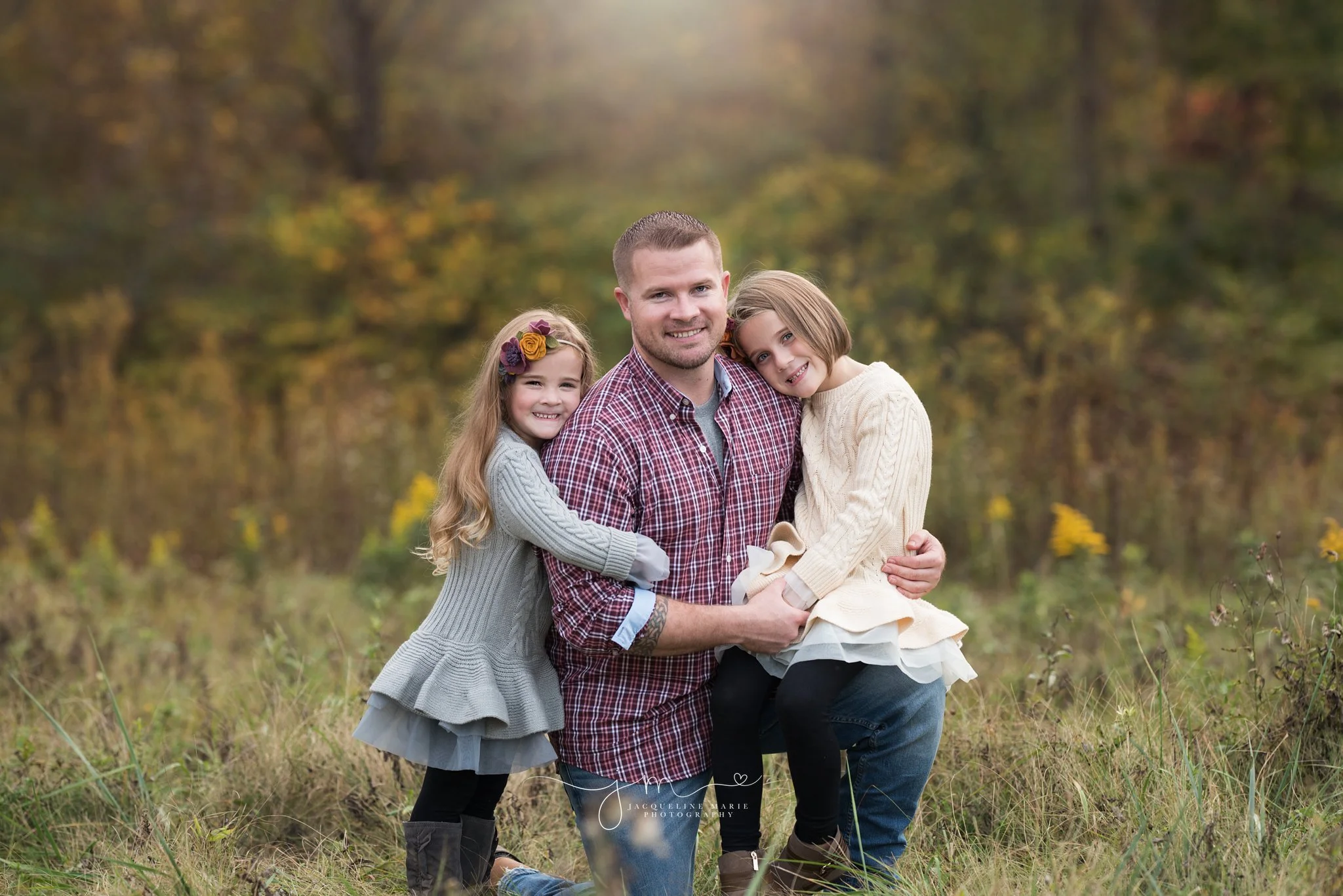 father kneels and hugs daughters for outdoor fall family photography in columbus ohio