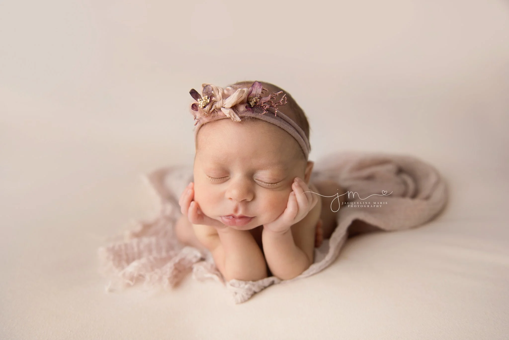 columbus ohio newborn baby girl wears pink and purple headband while posed with her chin in her hands for newborn photography session