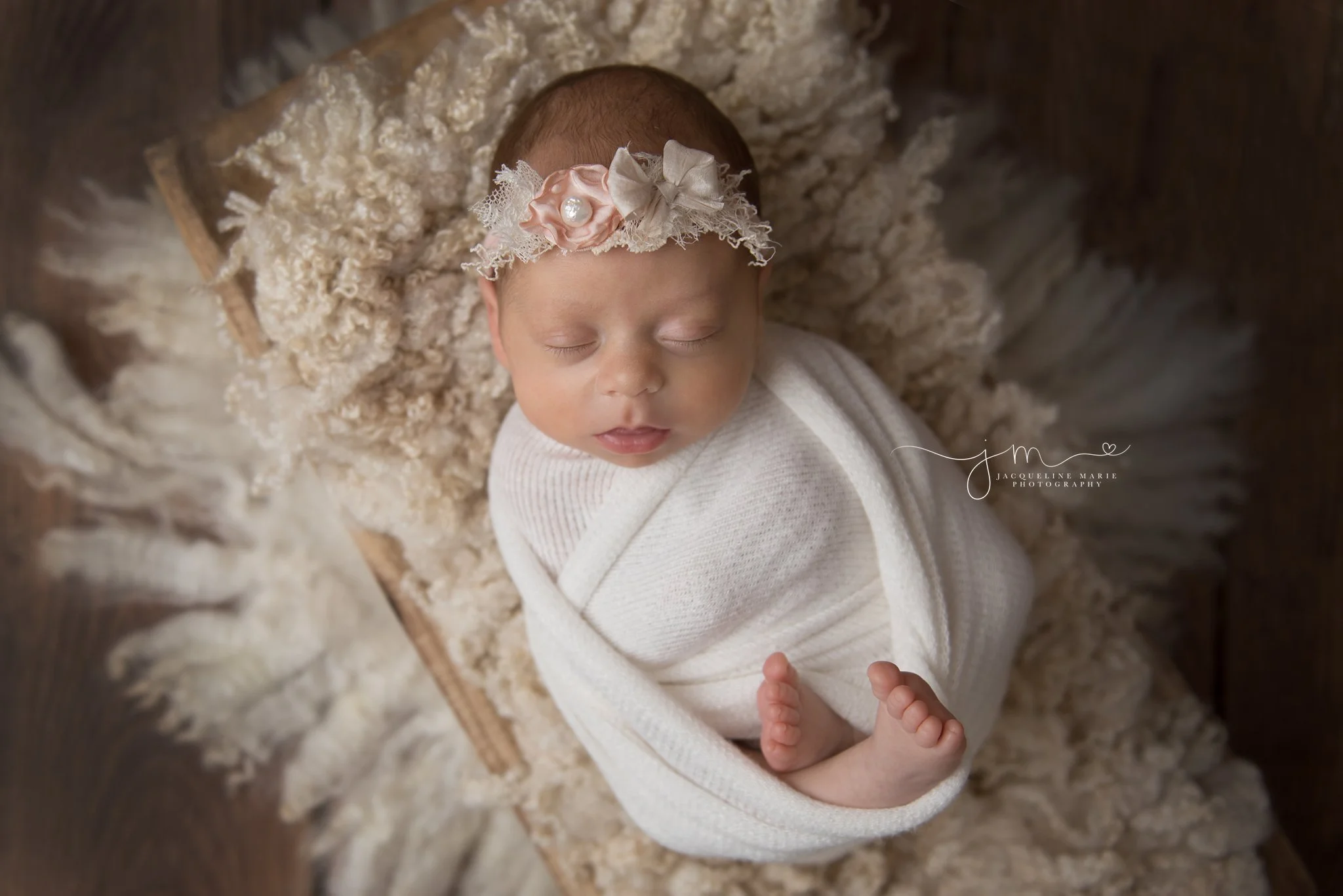 6 week old newborn baby girl wears pink and cream headband while swaddled at jacqueline marie photography studio in columbus ohio