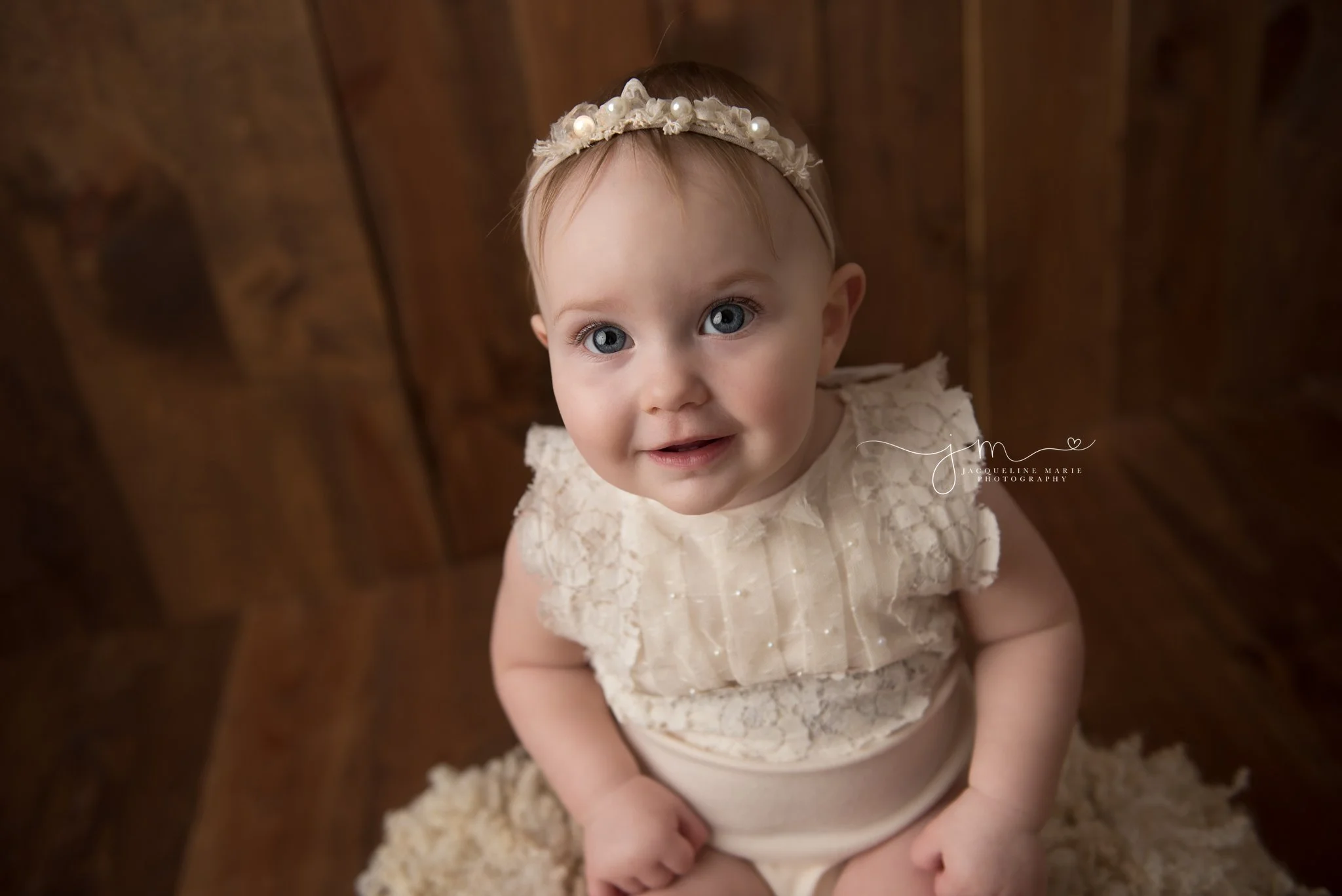 baby photographer in columbus ohio features images of baby on dark wood wearing a cream pearl romper