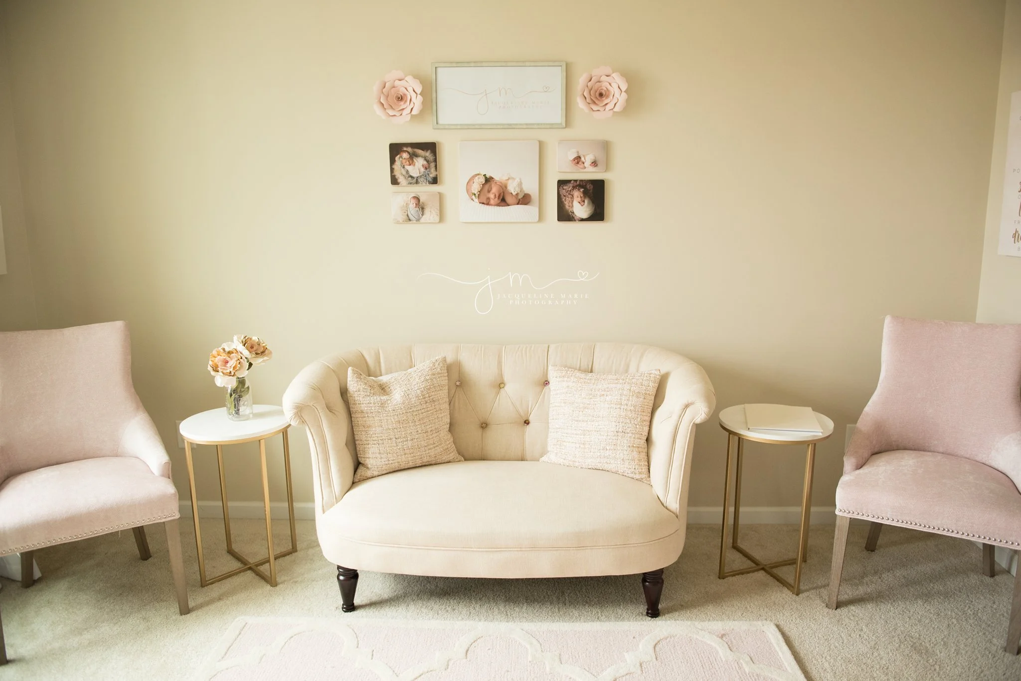 newborn photography studio inspiration features a cream couch and pink chairs to welcome families 