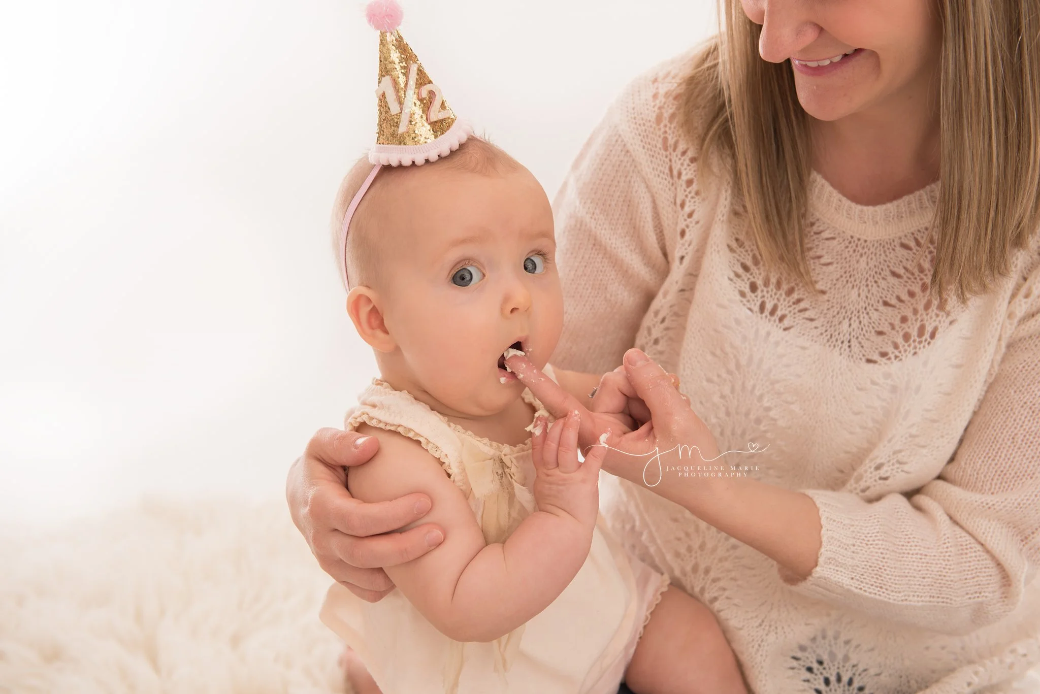6 month old baby girl enjoys a bite of a cupcake for her half birthday with her mommy