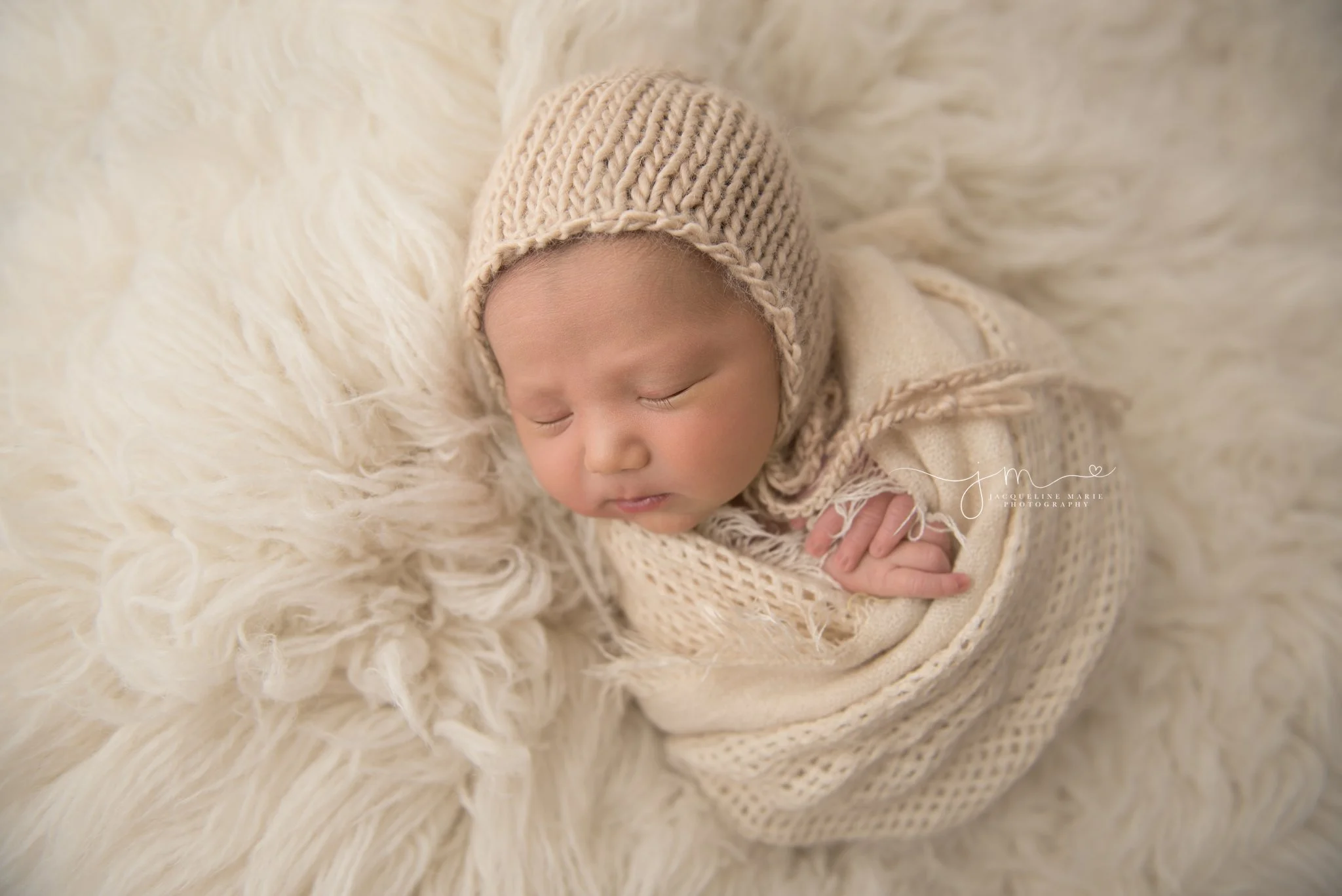 1 week old newborn baby boy is swaddled on a cream fur rug during newborn session at columbus ohio photography studio