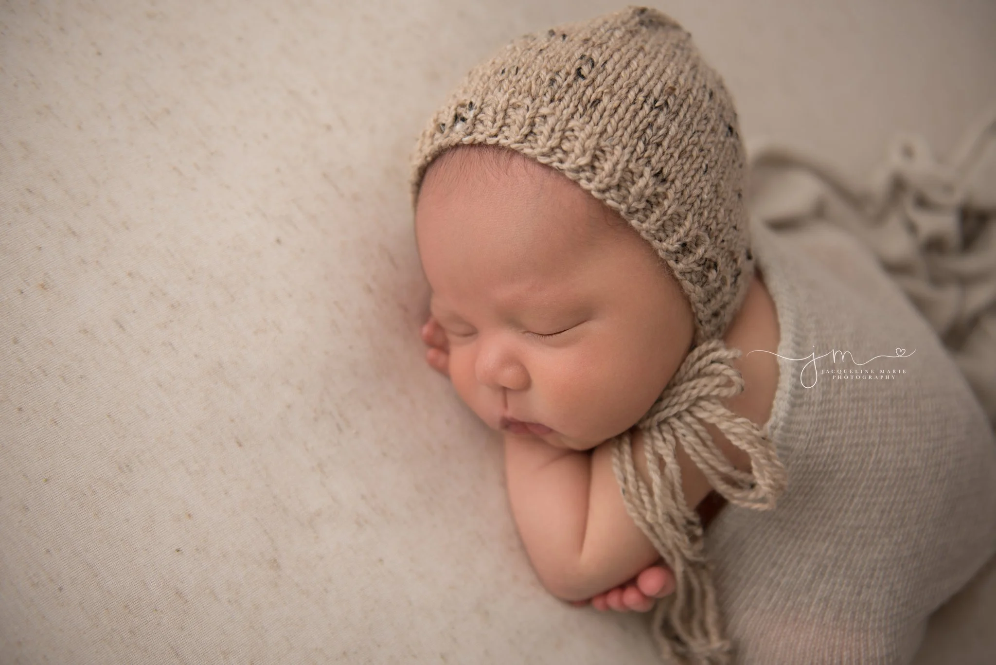 columbus ohio newborn photographer poses baby boy in tan bonnet and matching wrap
