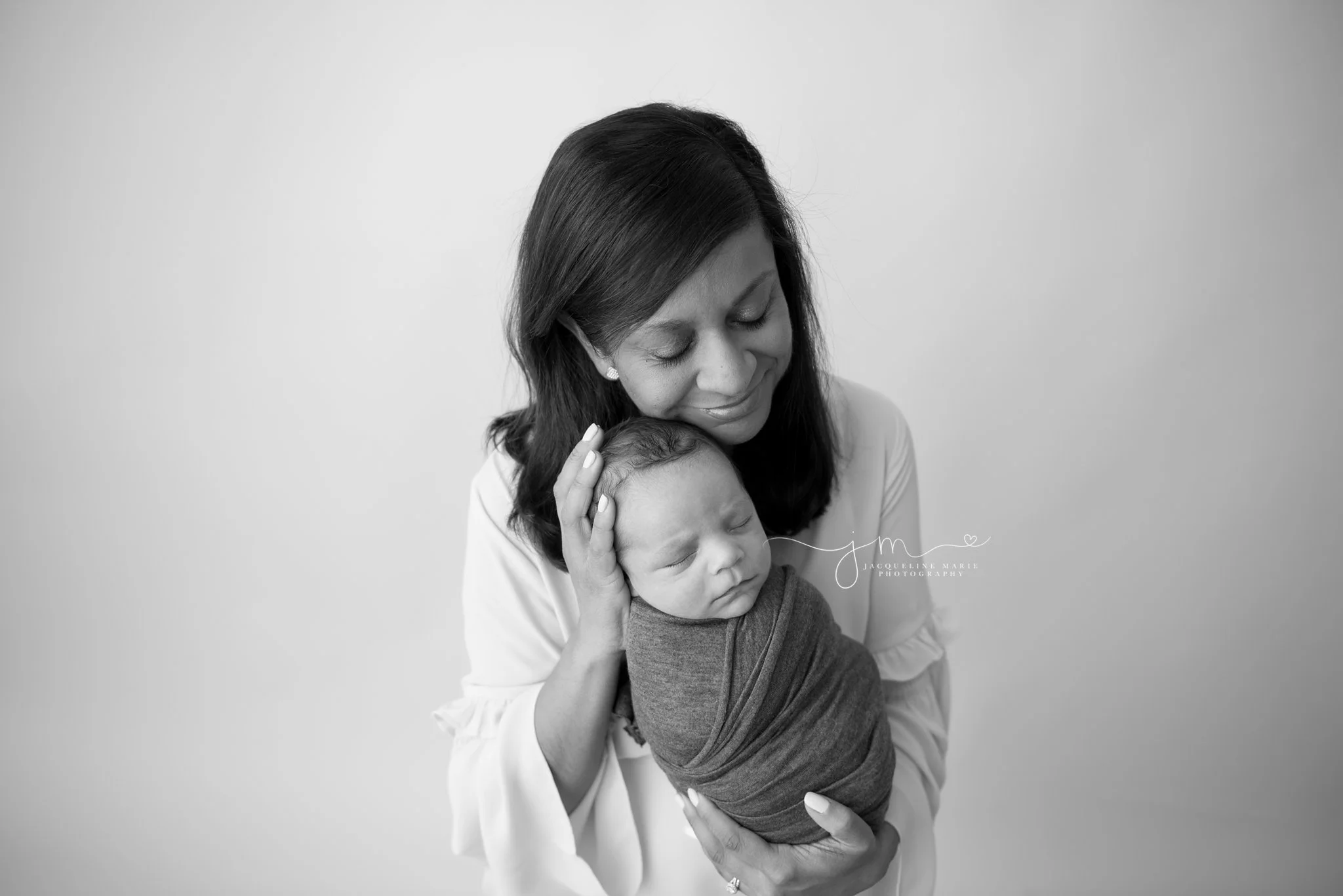mother holds newborn baby boy and smiles in columbus ohio newborn photography studio