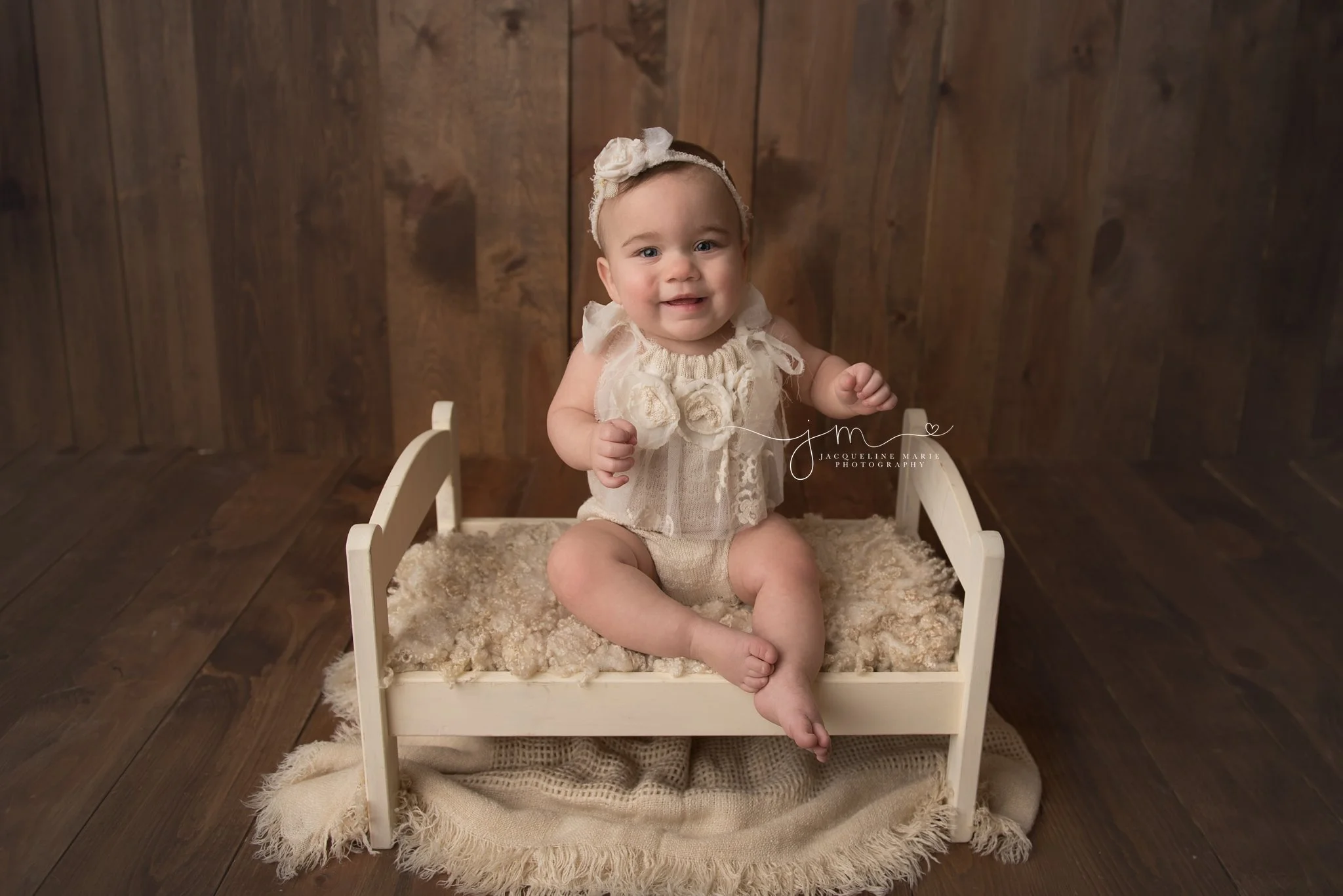 1 year old baby girl smiles wearing a cream romper for first birthday portraits in columbus ohio