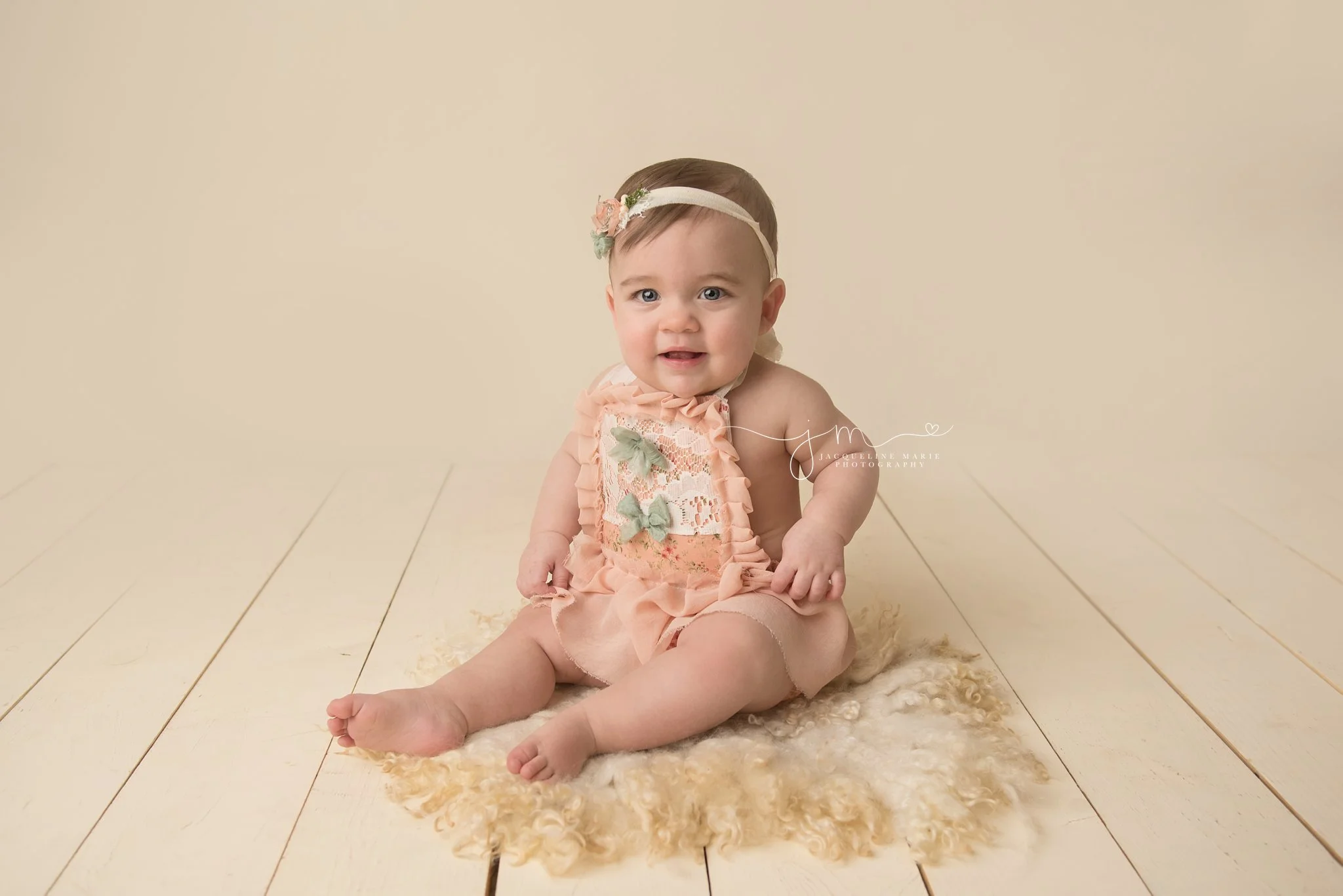columbus ohio baby photographer poses 1 year old in peach romper and matching headband for first birthday milestone pictures
