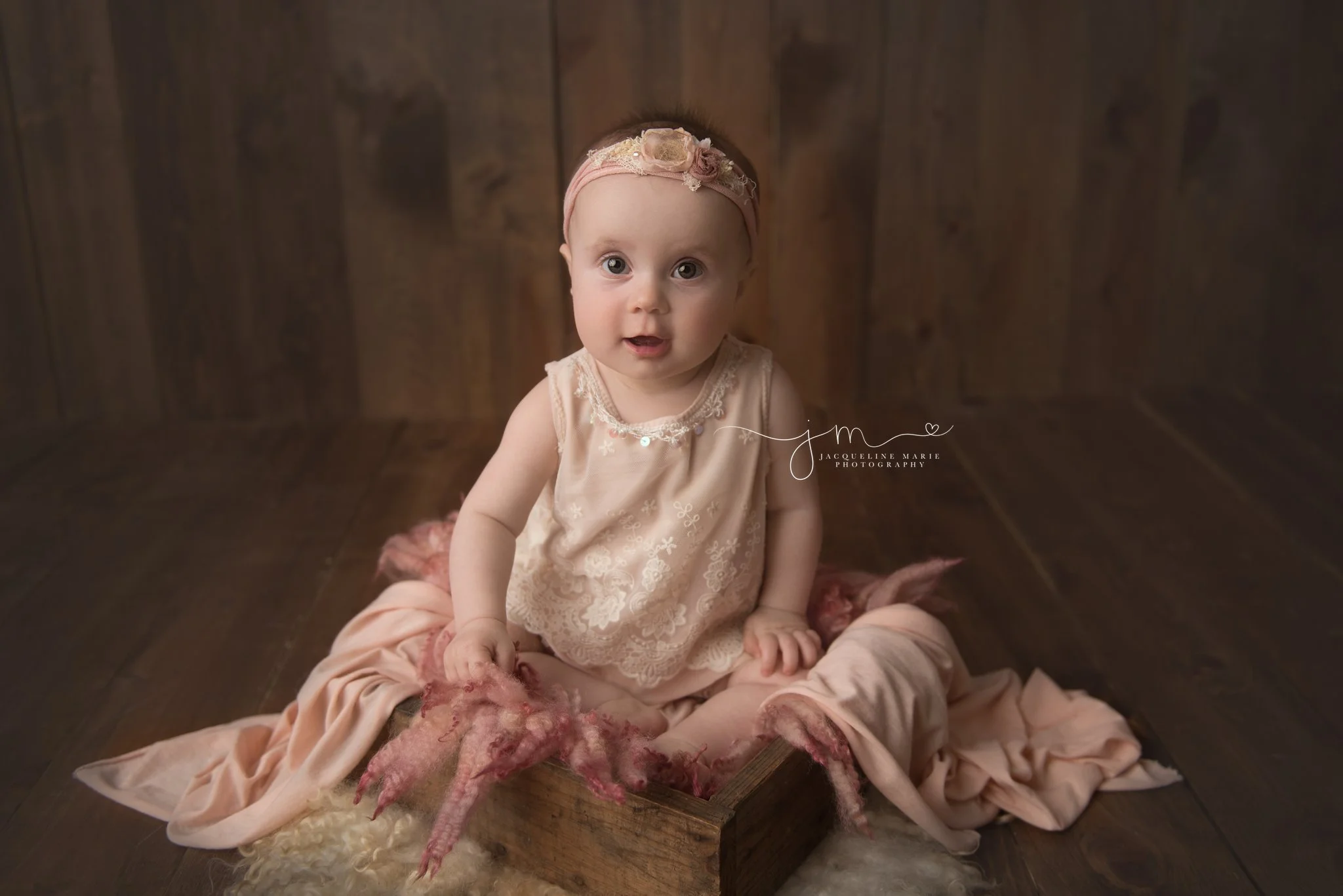 6 month old baby girl wears pastel pink romper and matching headband for baby milestone pictures in columbus ohio