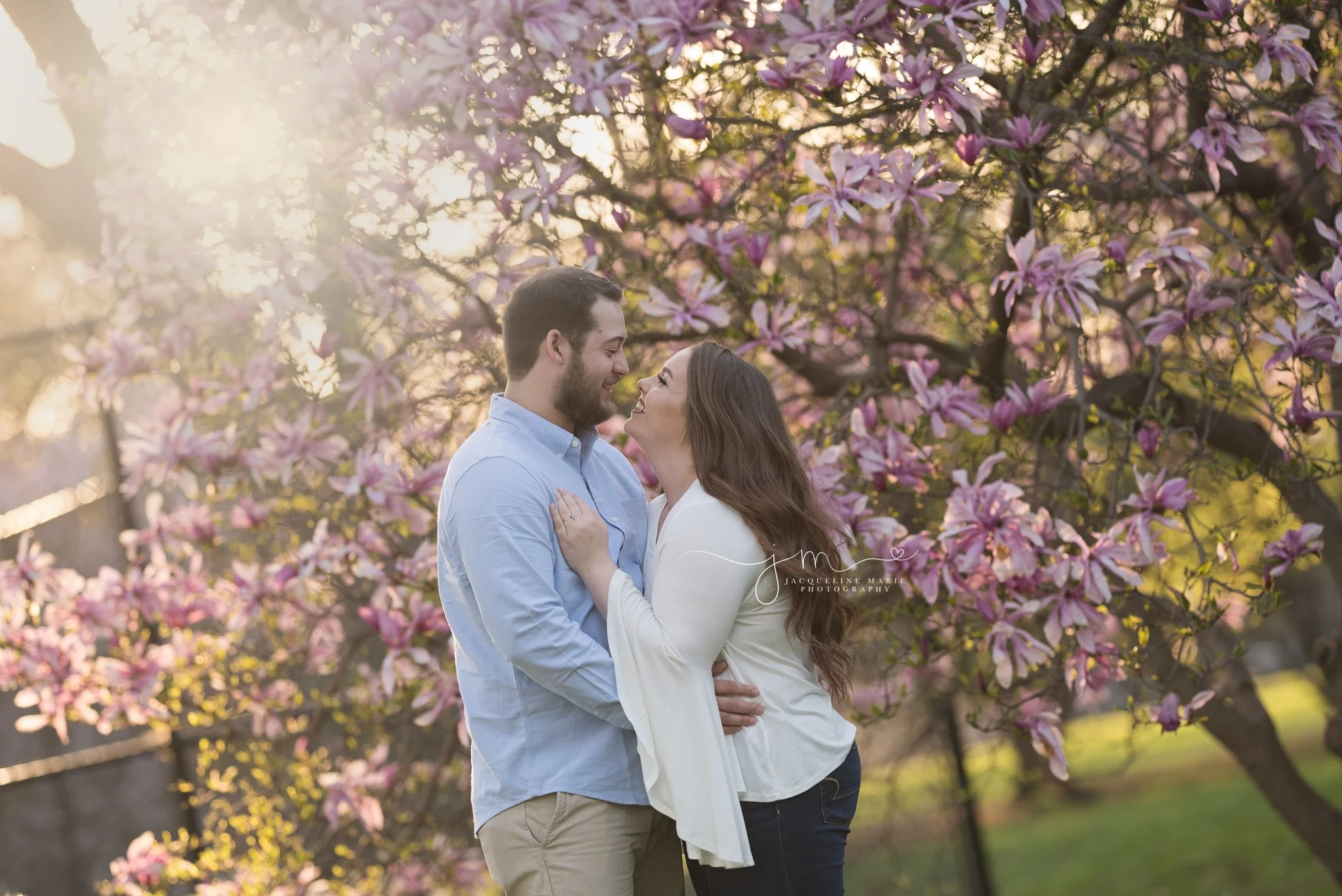 mother and father smile during sunset next to magnolia tree in Columbus ohio