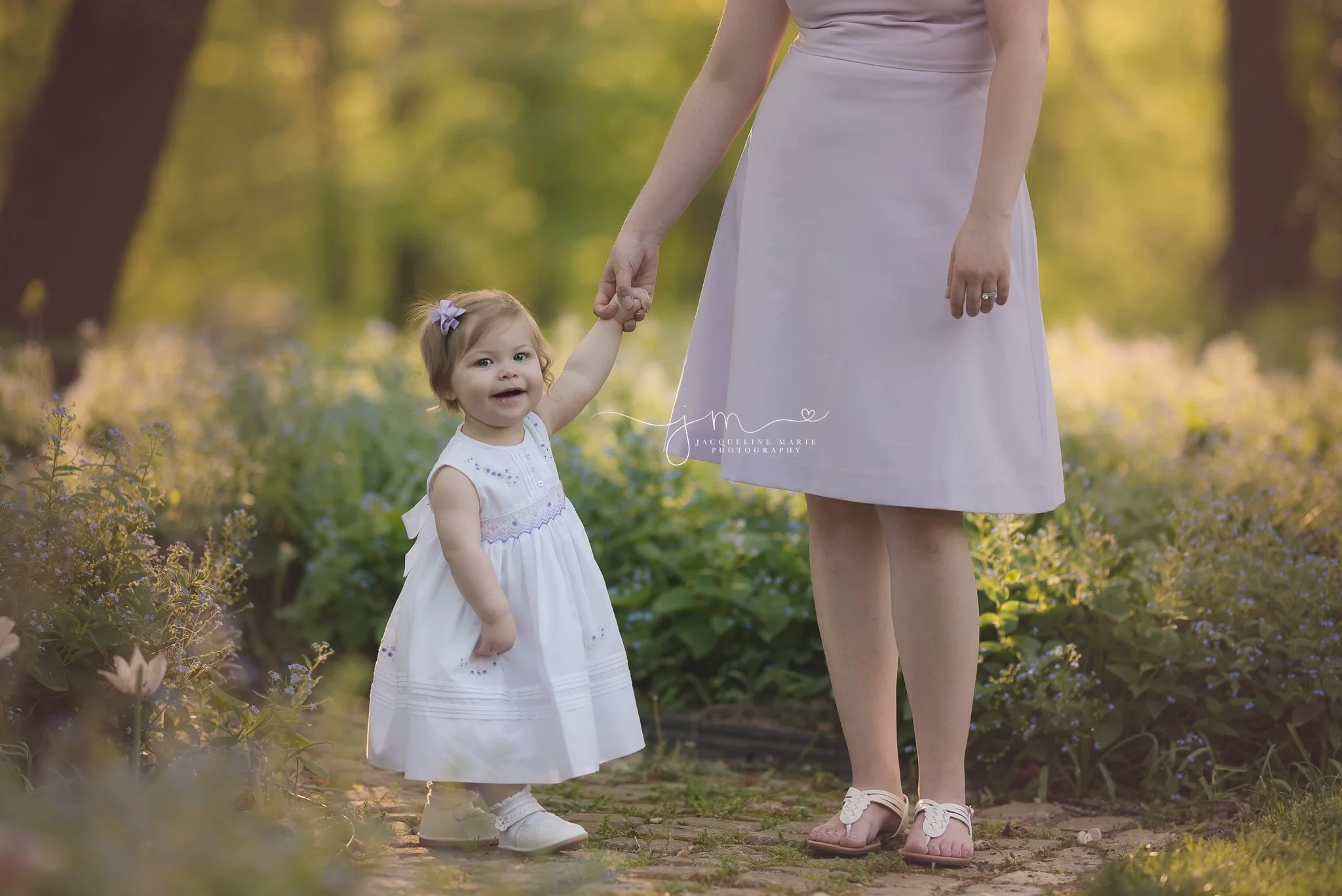 1 year old little girl holds mother's hand while standing at Innis woods during sunset in columbus ohio