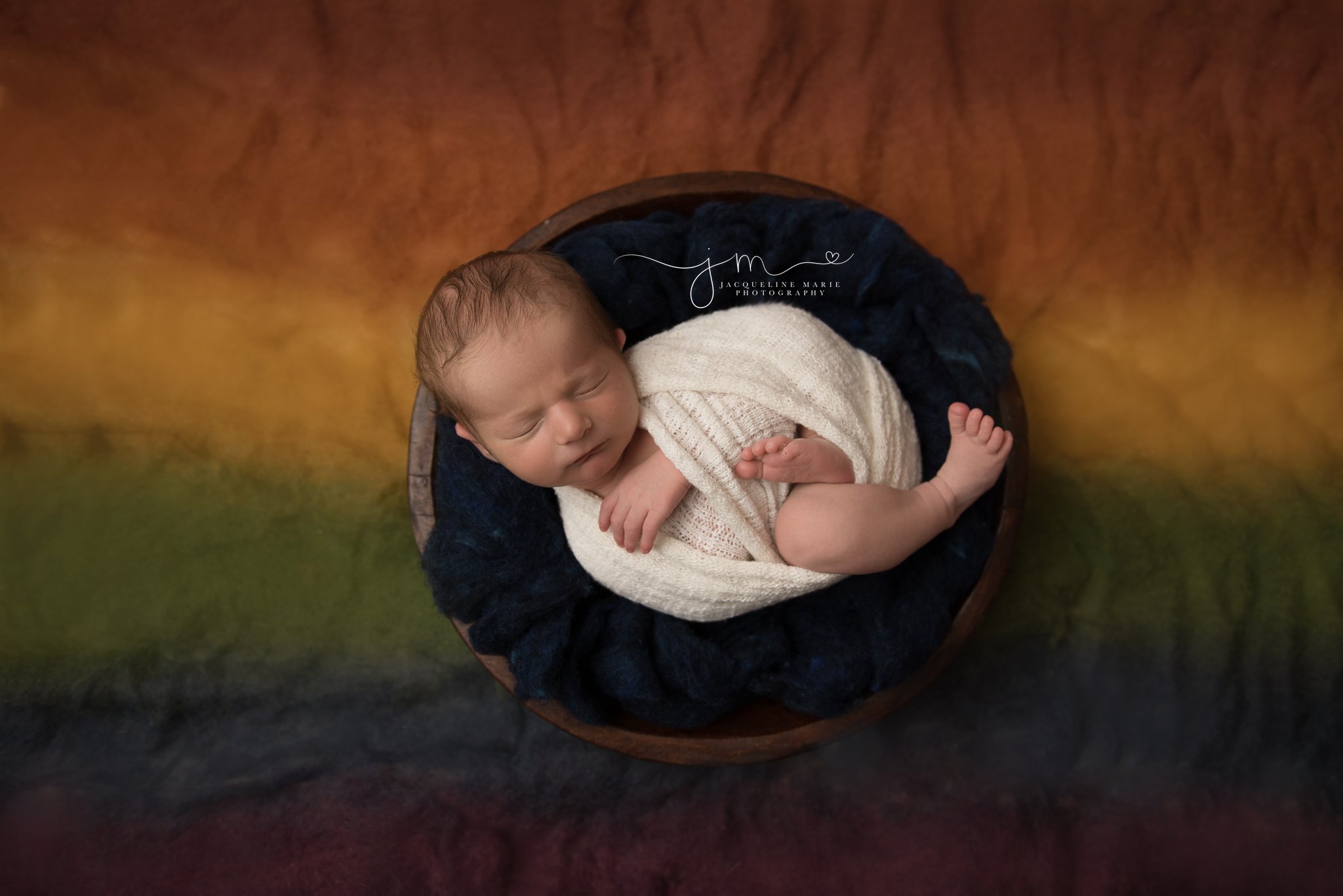 rainbow baby boy swaddled in cream wrap and rainbow blanket in columbus ohio newborn photography studio